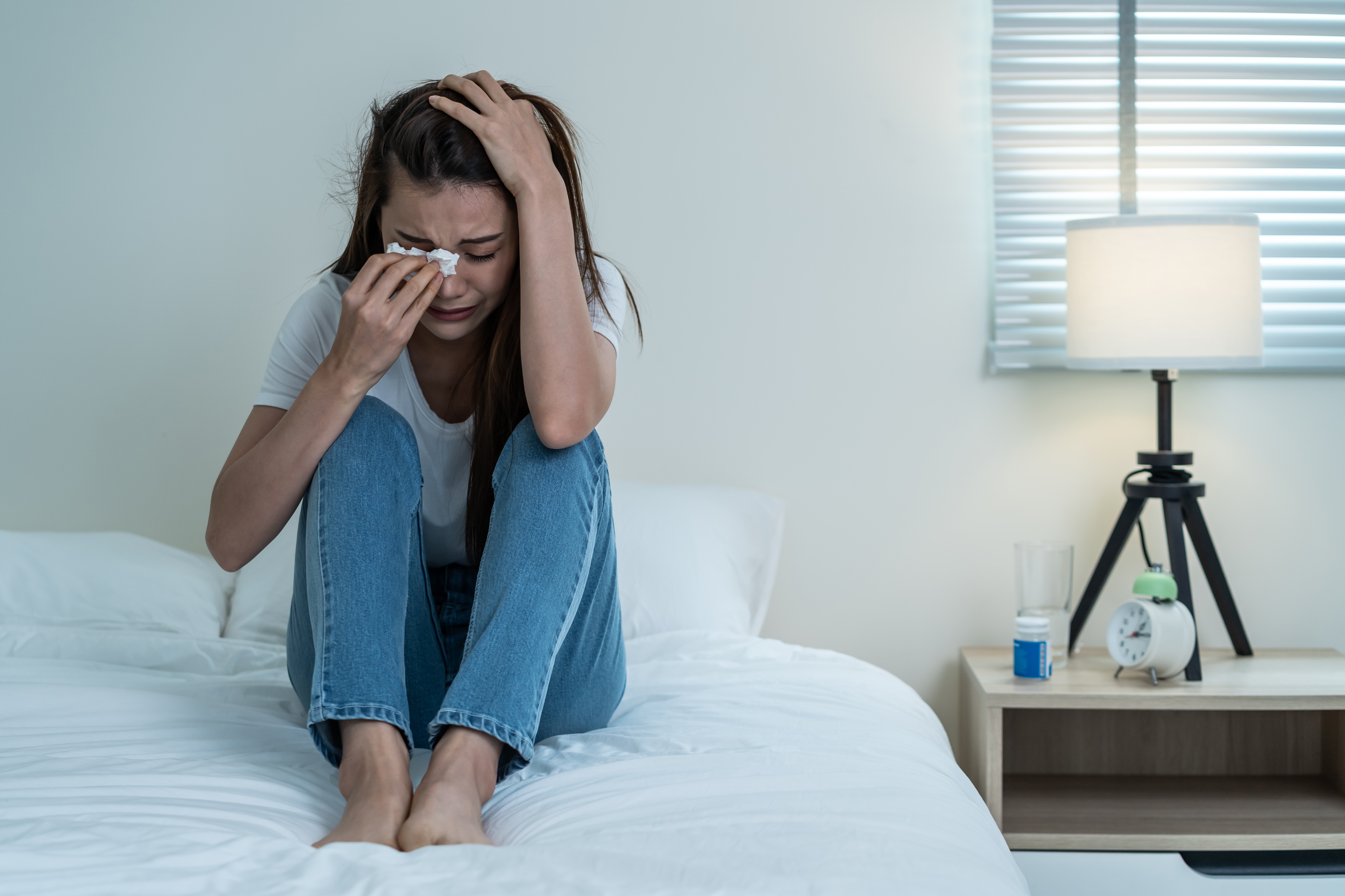 Girl is crying sitting on the bed | Source: Shutterstock.com