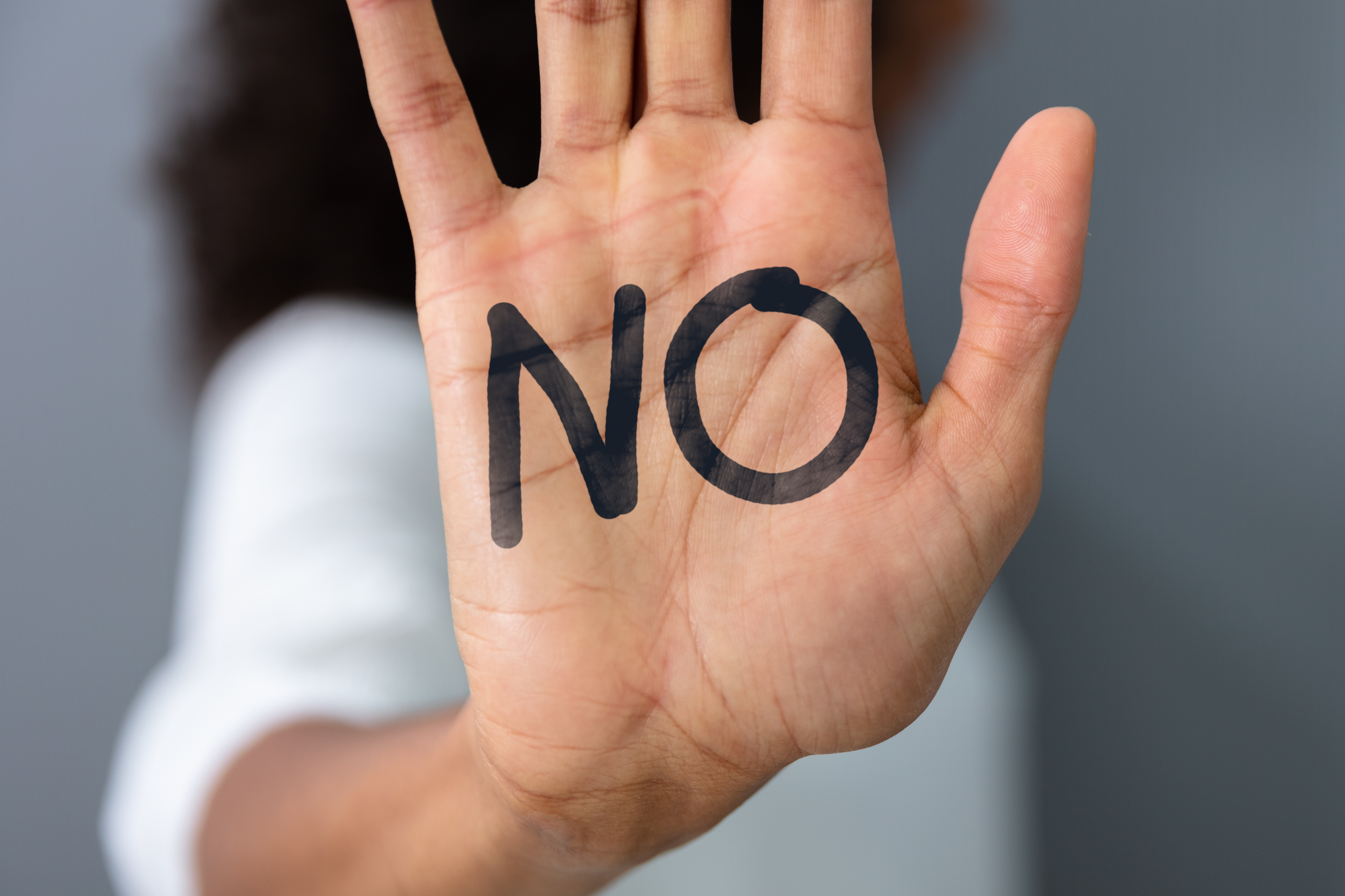 A woman's raised hand with 'No' text | Source: Shutterstock