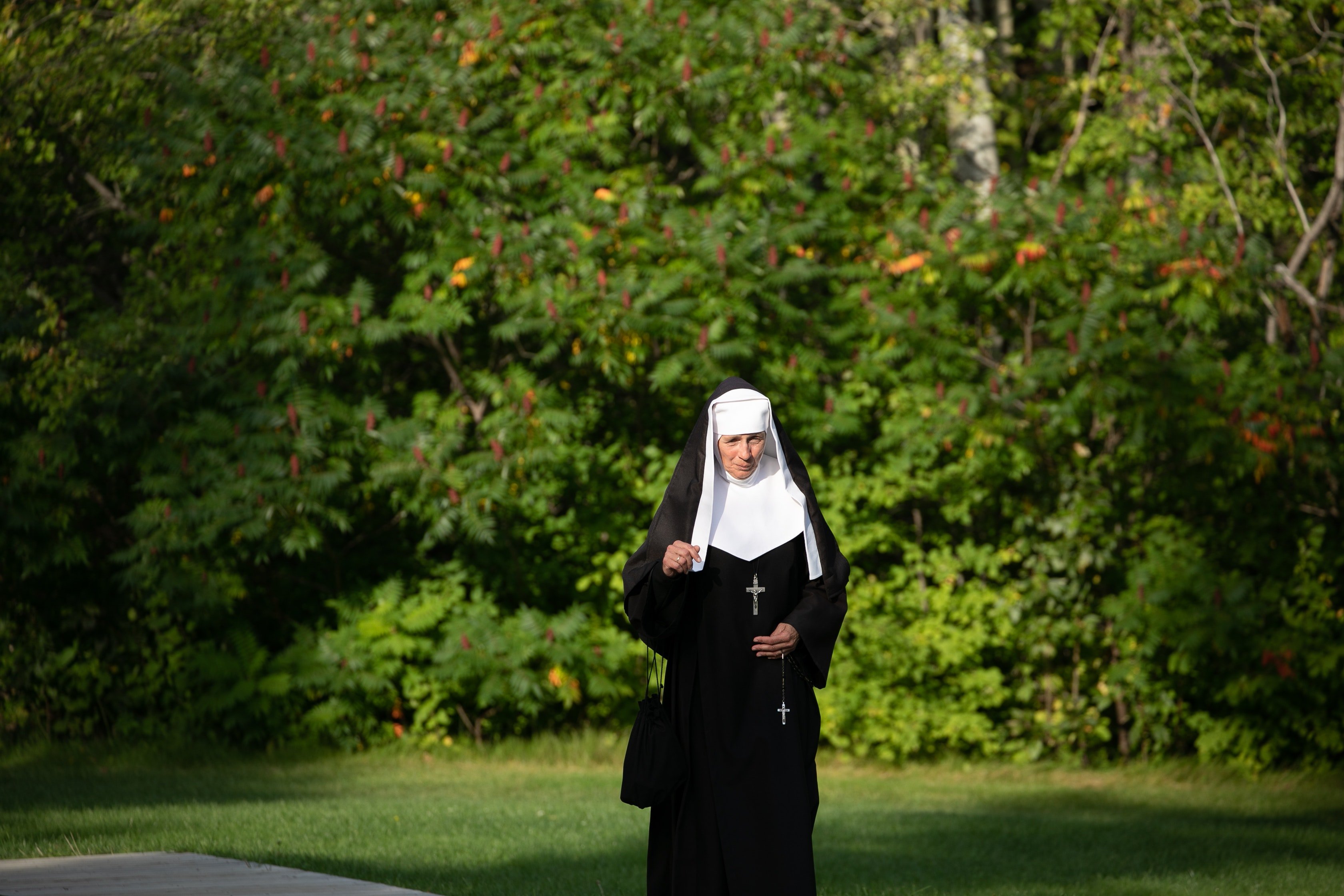 A nun holds a cross in her hand and walks down the street | Photo: Pexels/Mathieu Acker 