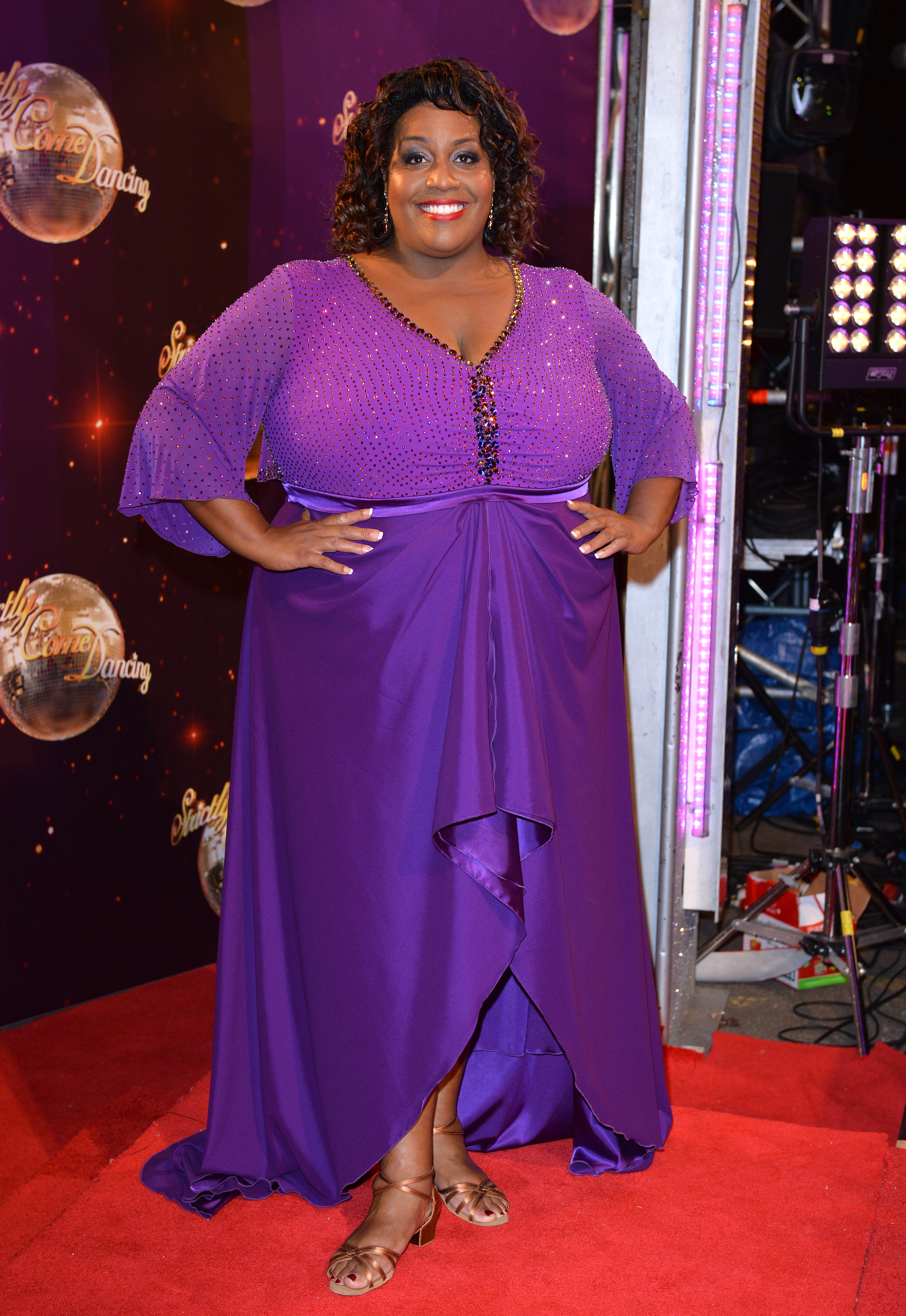 Hammond commands attention with her hands on her hips at the glittering launch of "Strictly Come Dancing" at Elstree Studios on 2 September 2014. In a purple gown with sparkling neckline details, she lights up the red carpet with a beaming smile against the show’s iconic backdrop.