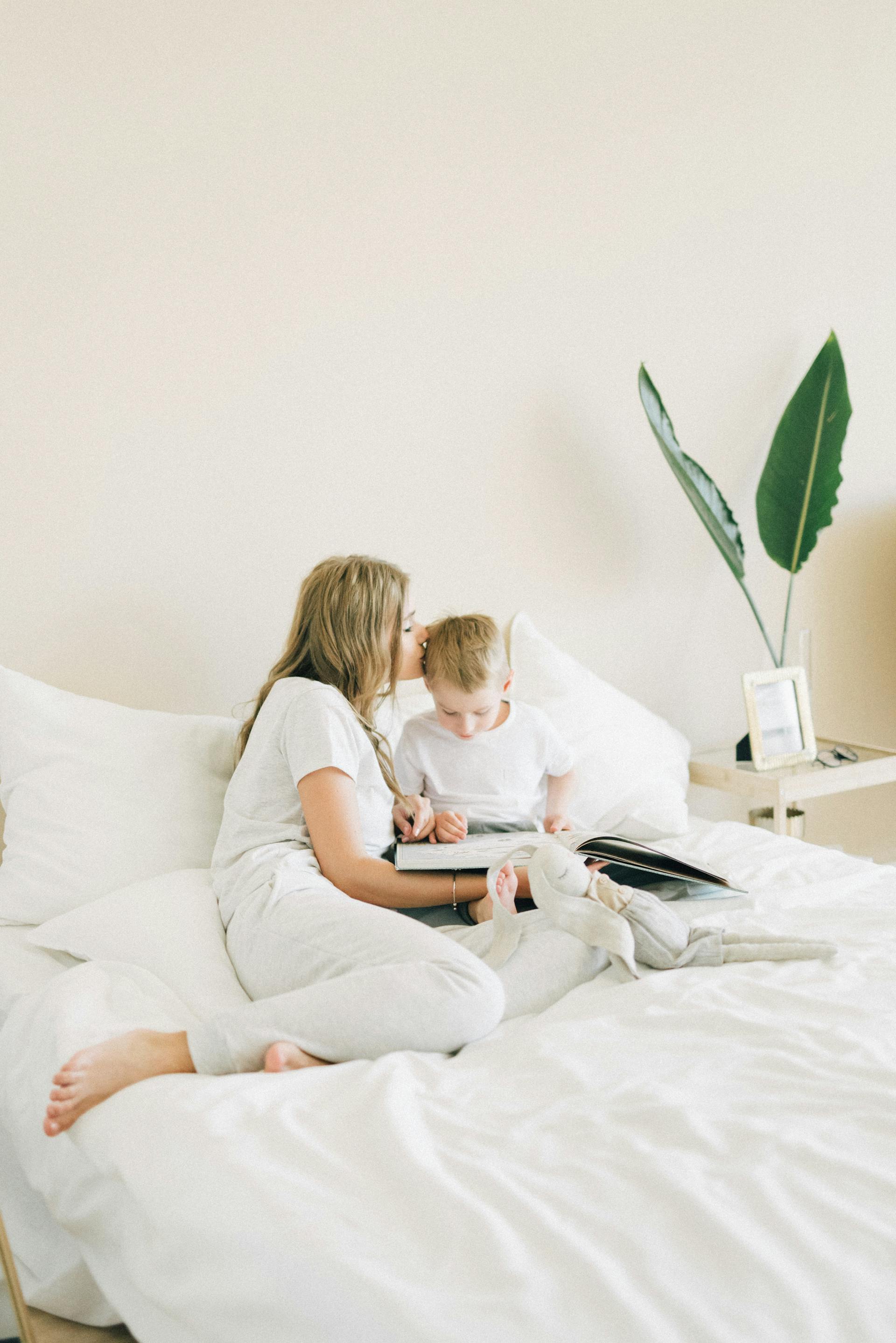 A woman tucking her son into bed | Source: Pexels