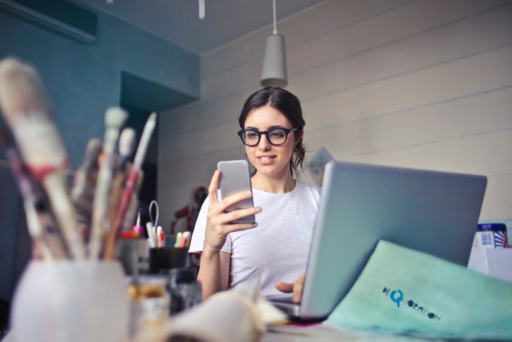 Une jeune femme sourit en lisant un message texte. | Pexels
