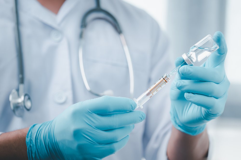 Profesional de la salud con una inyectadora y un frasco de vacuna contra el coronavirus en sus manos. | Foto: Shutterstock