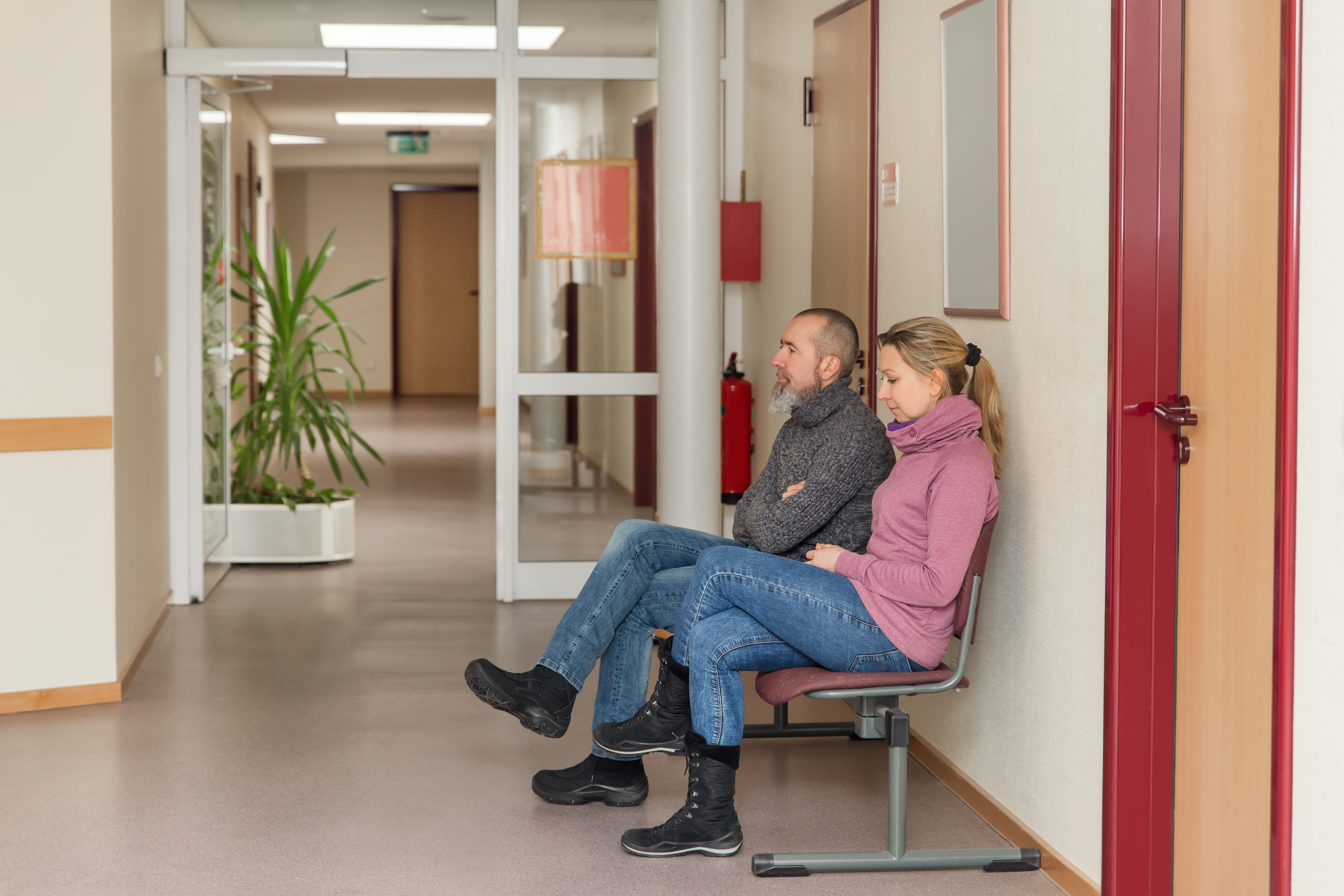 Nervous couple is sitting in corridor and waiting | Source: Shutterstock.com