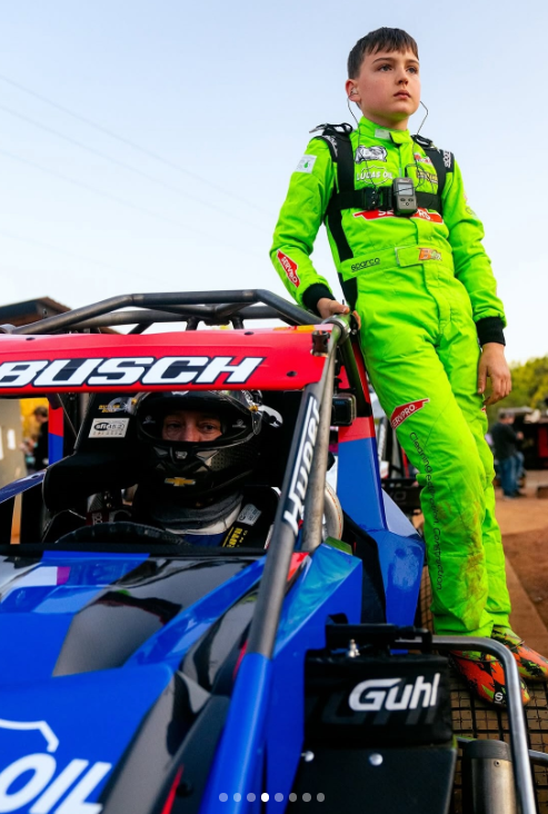 Kyle Busch sits inside a race car as his son Brexton stands on the side of the vehicle in his racing suit | Source: Instagram/rowdybusch