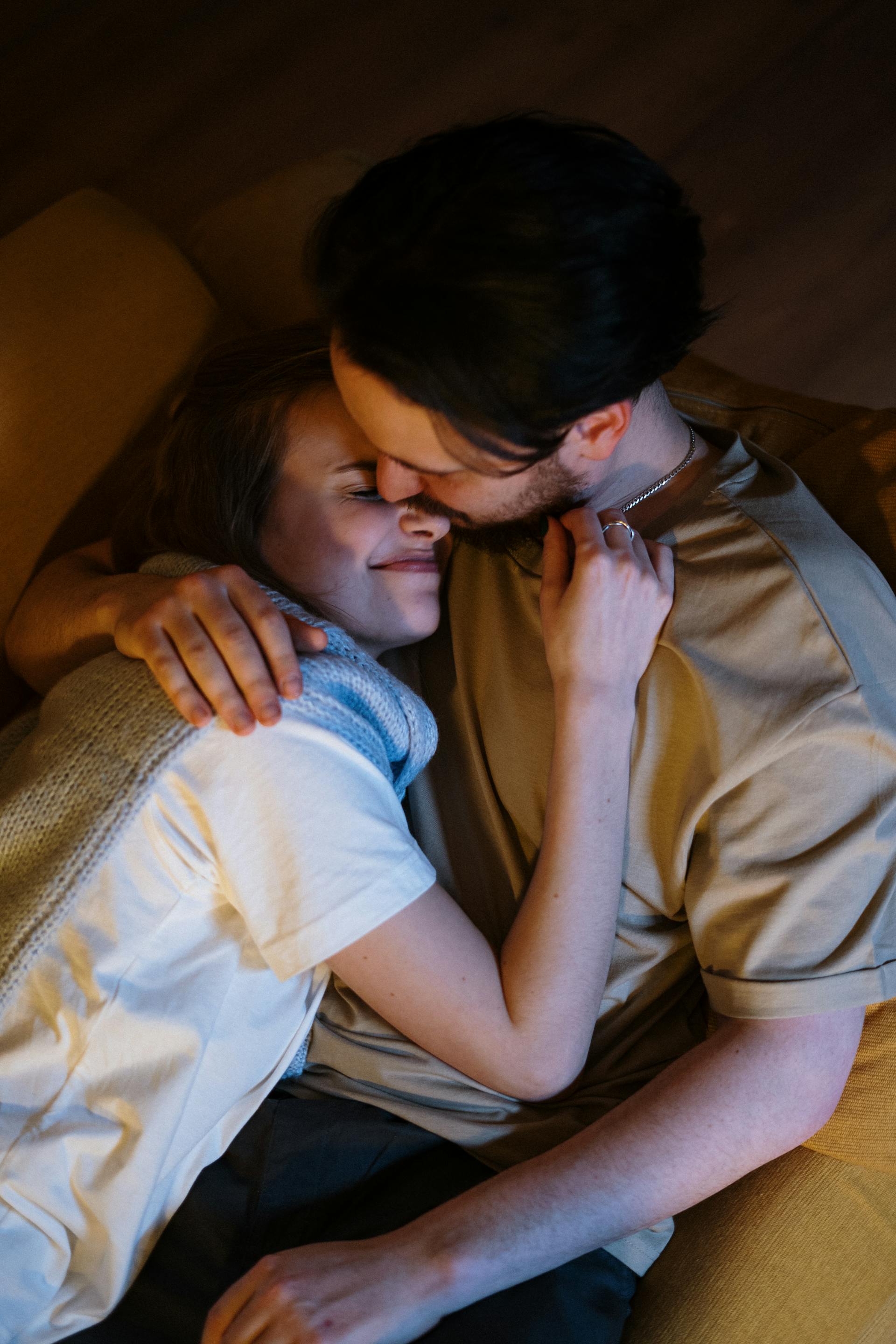 A romantic couple embracing each other on the couch | Source: Pexels