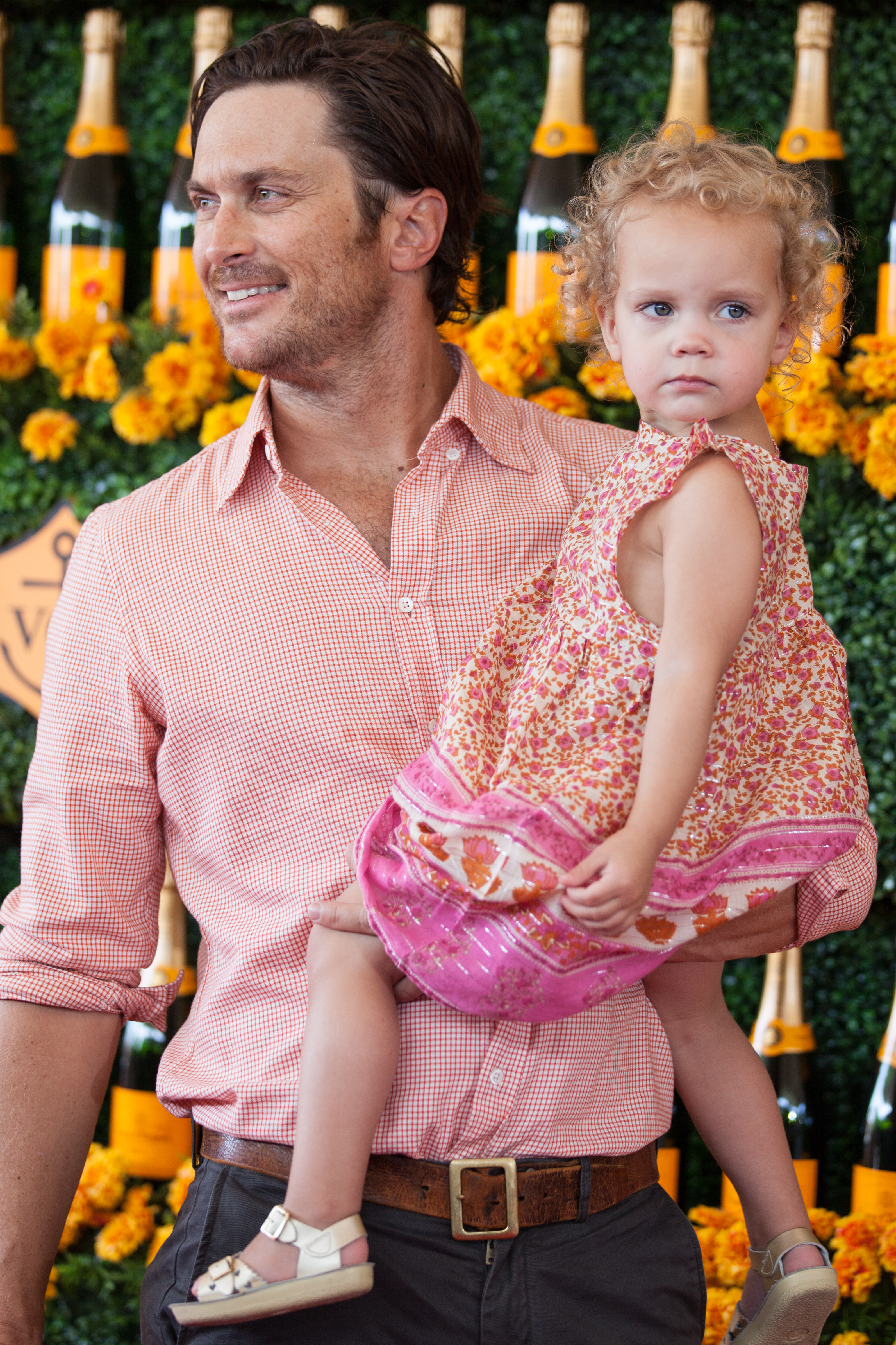 In this heartwarming moment from 2015, Oliver Hudson cradles his young daughter Rio at the Veuve Clicquot Polo Classic. With a gentle smile and proud eyes, the actor poses on the red carpet, capturing a sweet father-daughter bond that charmed fans early on.
