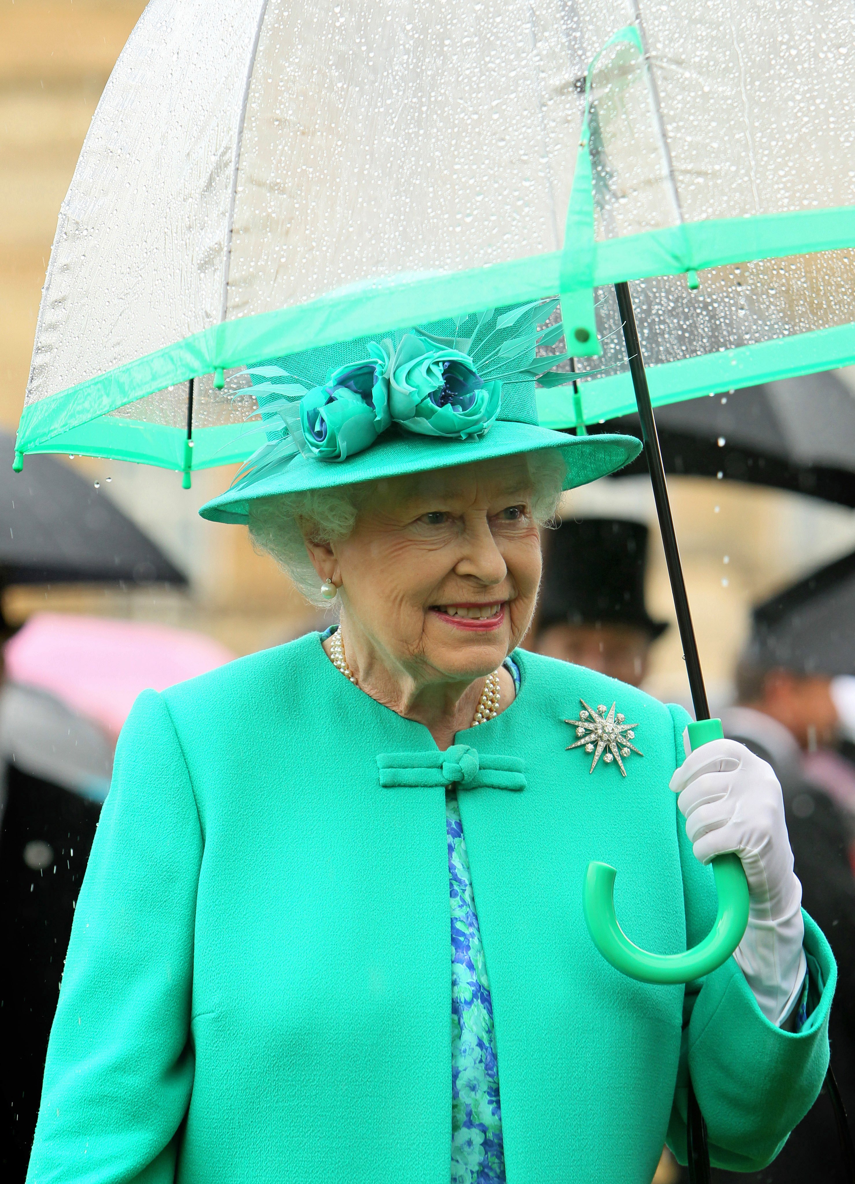 Queen Elizabeth II shelters from the rain under an umbrella at Buckingham Palace on July 19, 2011 in London, England | Photo: Getty Images