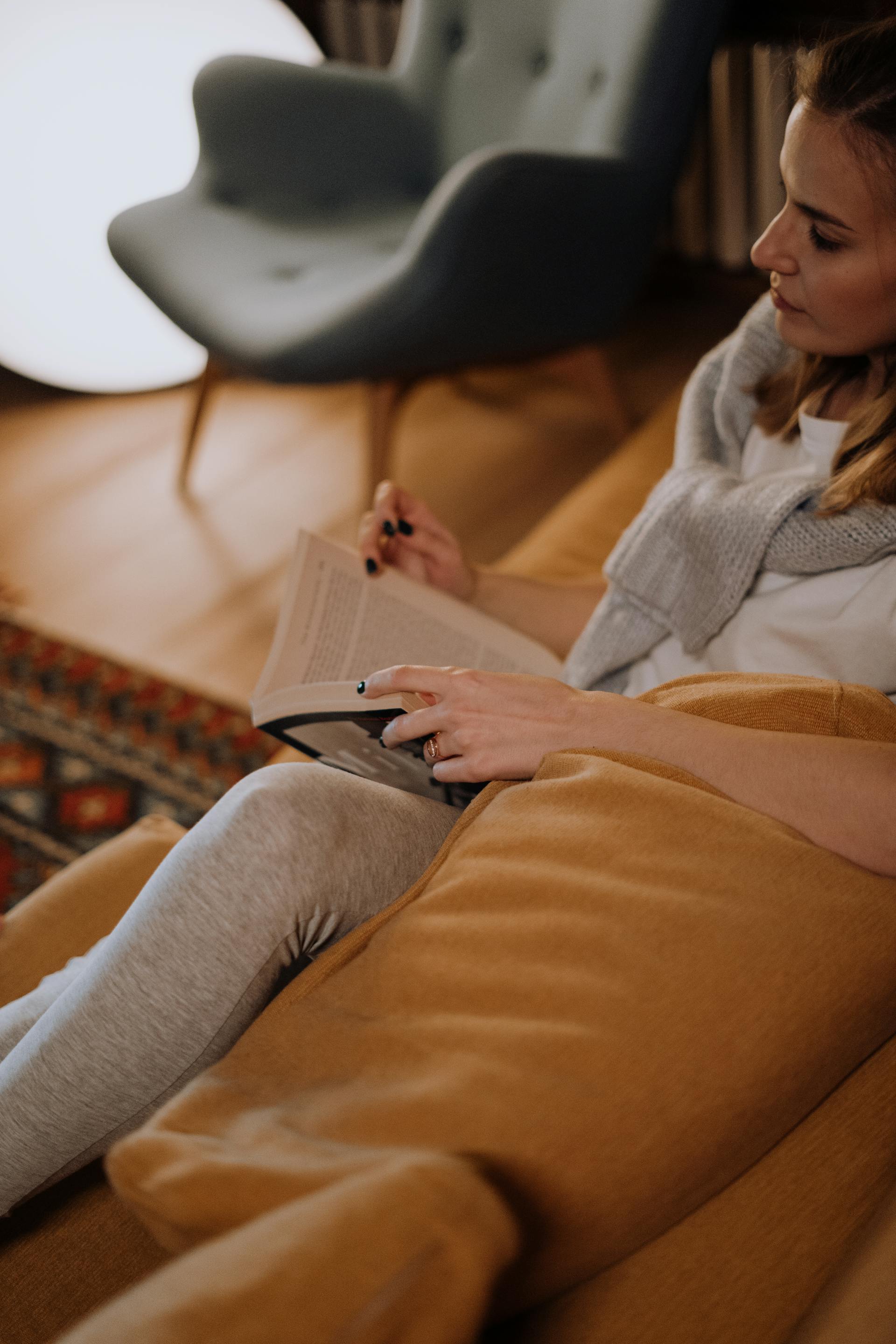 A woman with a book on the couch | Source: Pexels