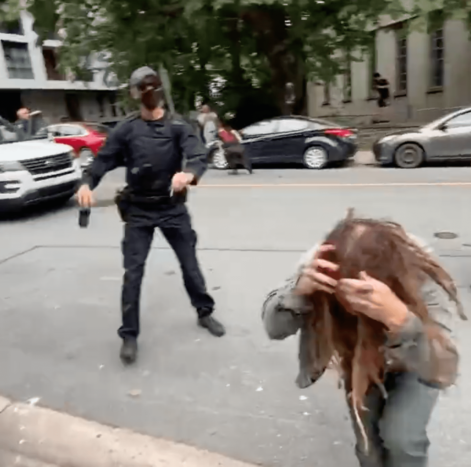 A protestor covers their face and runs away from a police officer | Photo: Twitter/zwoodford