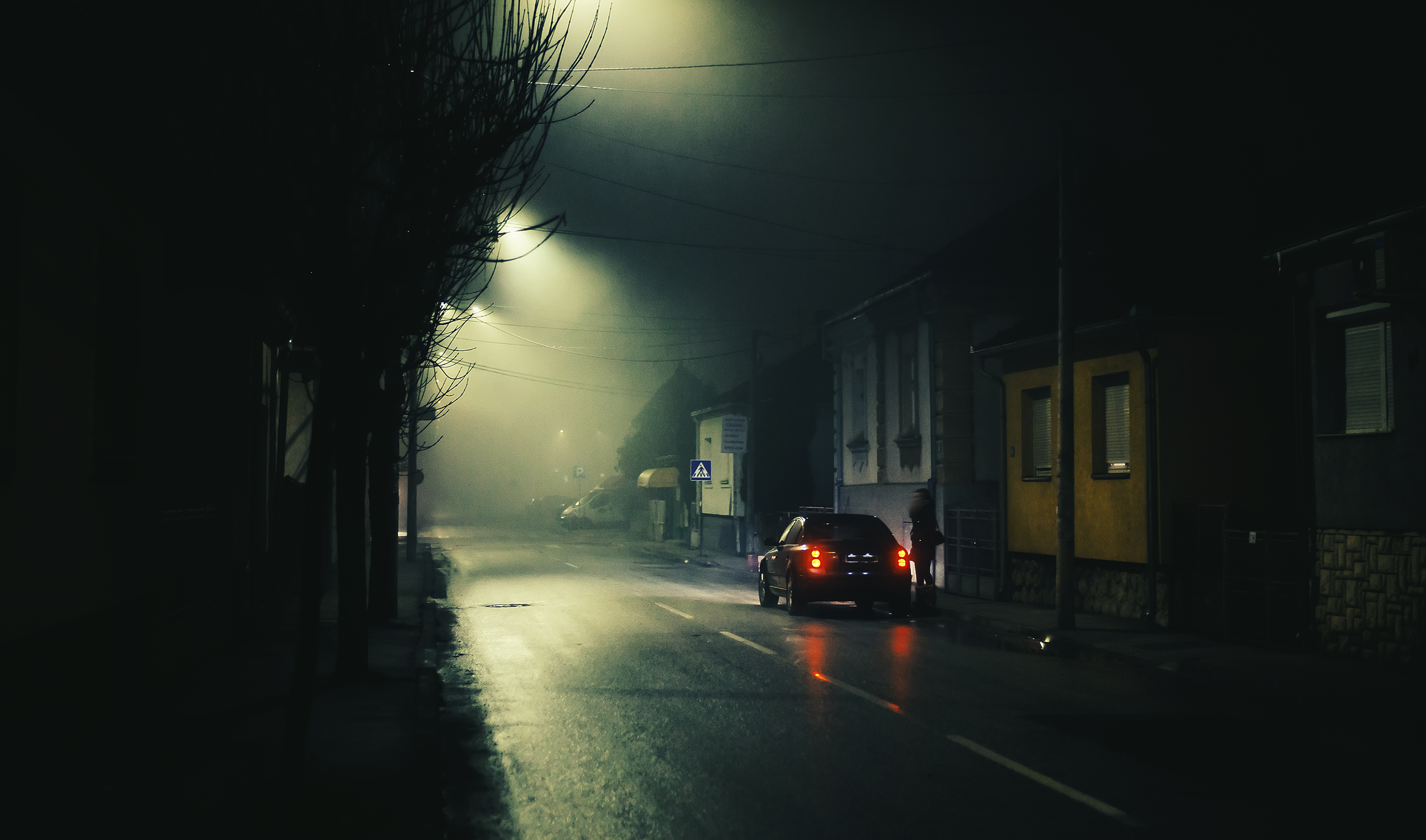 Night scene on foggy street of a small town, lonely woman and one car. | Source: Shutterstock