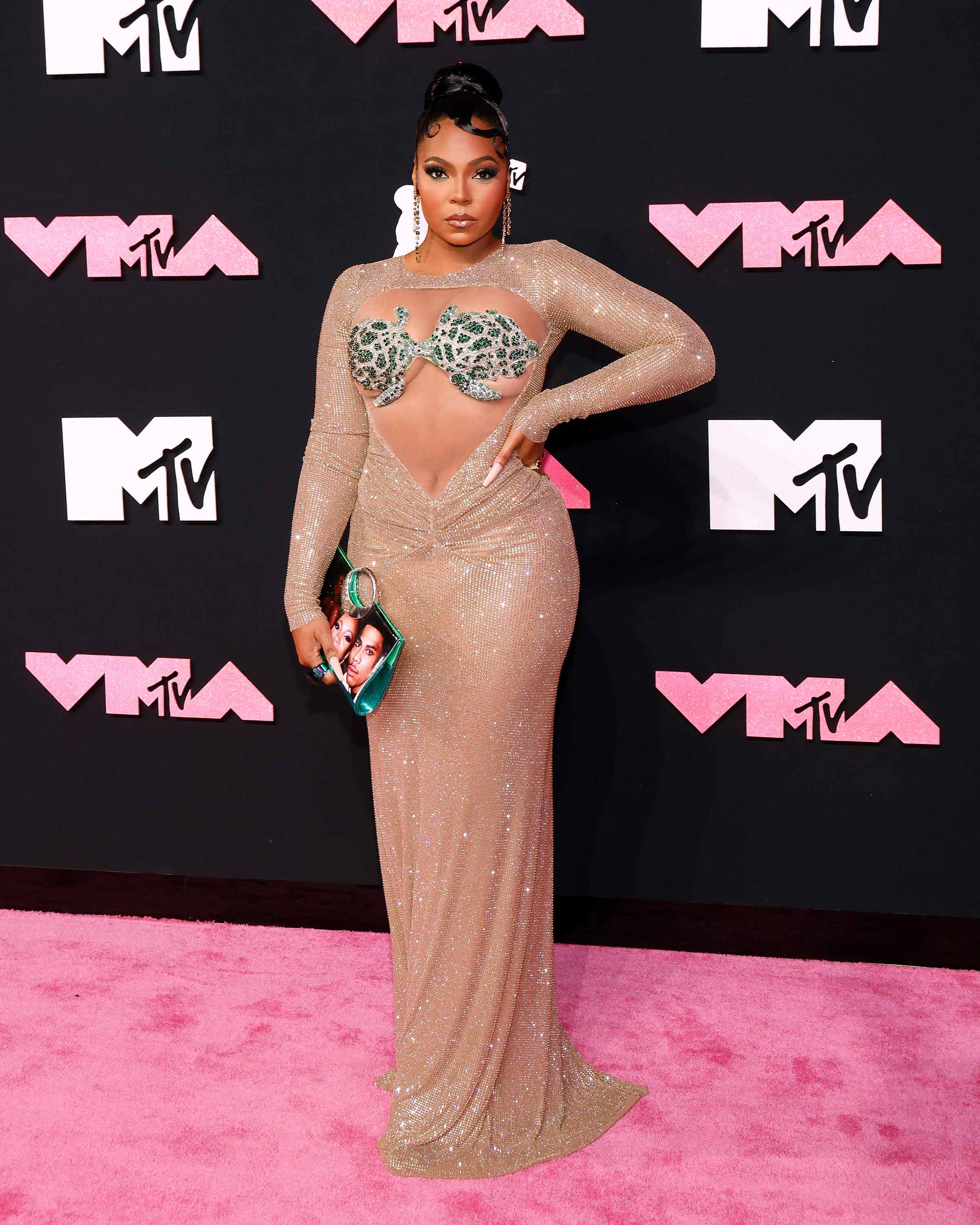 Ashanti attends the MTV Video Music Awards at the Prudential Center in Newark, New Jersey, wearing a stunning nude-colored bodycon dress that accentuates her curves. The gown features a sheer front revealing her printed bra, and she strikes a confident pose, looking absolutely gorgeous.