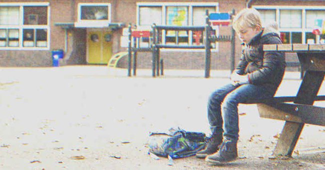 A kid sitting on a bench outside of school | Source: Shutterstock