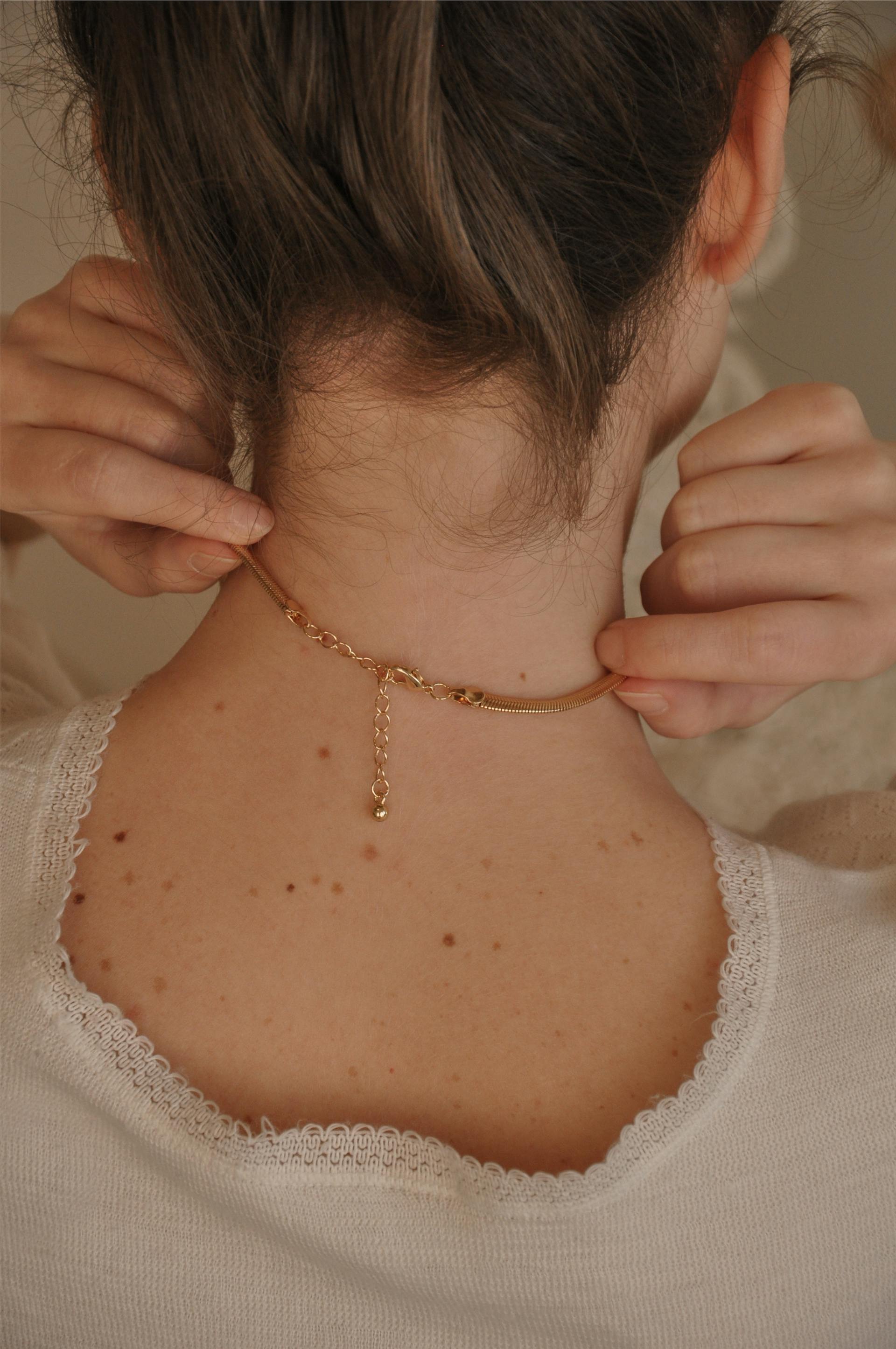 A back view of a woman touching her necklace | Source: Pexels