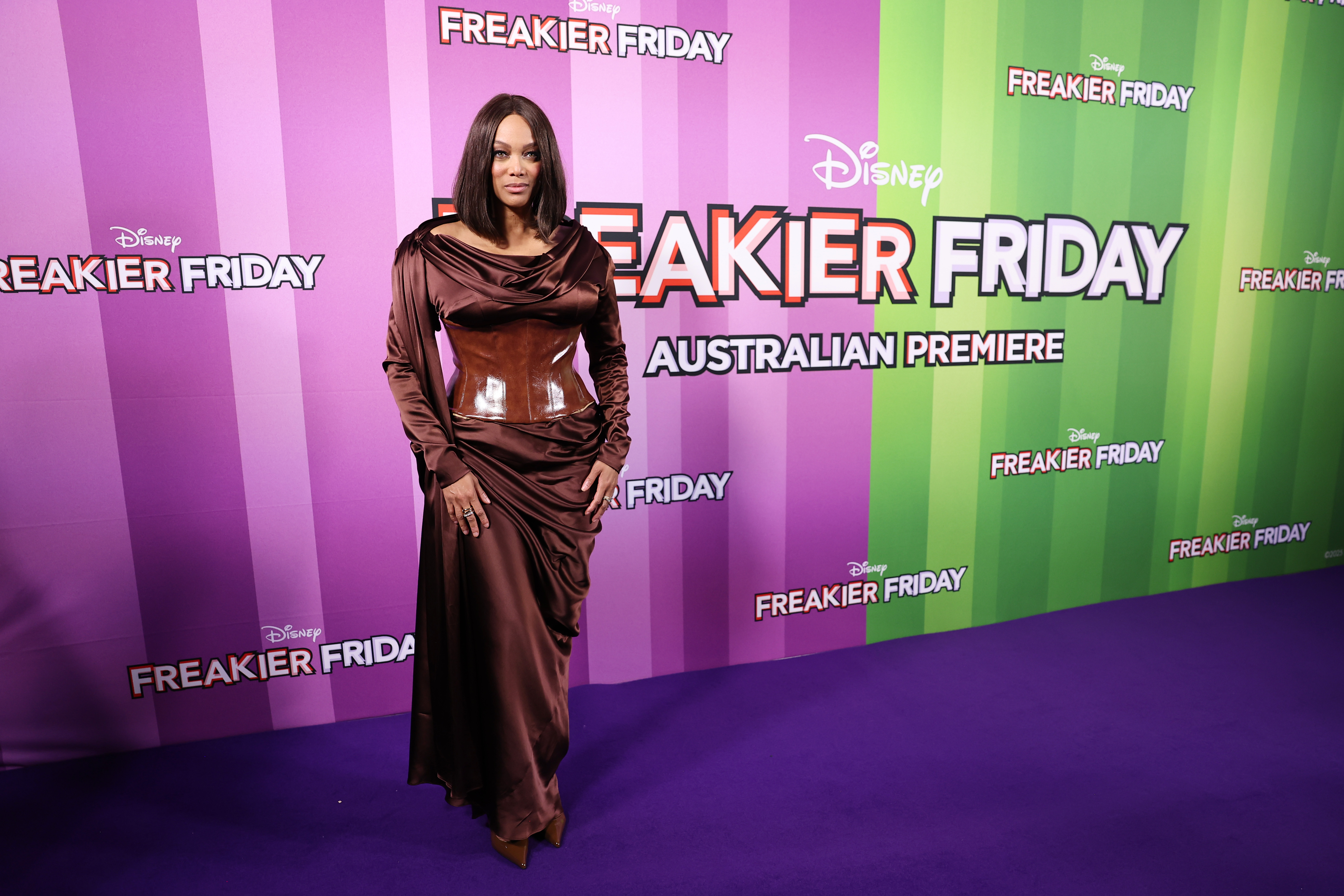 At the "Freakier Friday" Australian premiere on August 5, 2025, Tyra Banks turned heads in a chocolate-brown satin gown with a draped neckline and leather corset, styled with a sleek bob and minimal makeup that let her striking look command the purple carpet.
