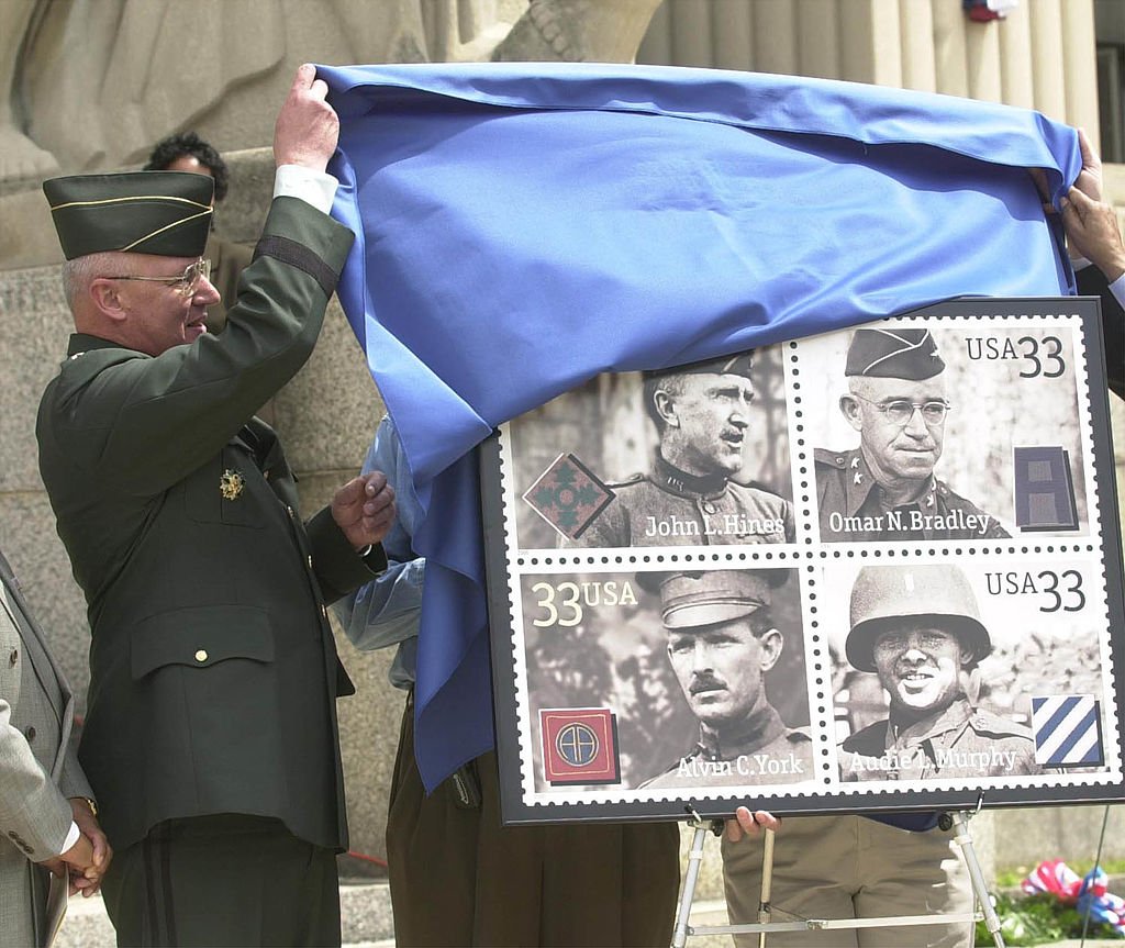 Major General Thomas Plewes unveils the new "Distinguished Soldiers" stamp that honors Alvin C. York, John L. Hines, Audie L. Murphy, and Omar N. Bradley | Source Getty Images