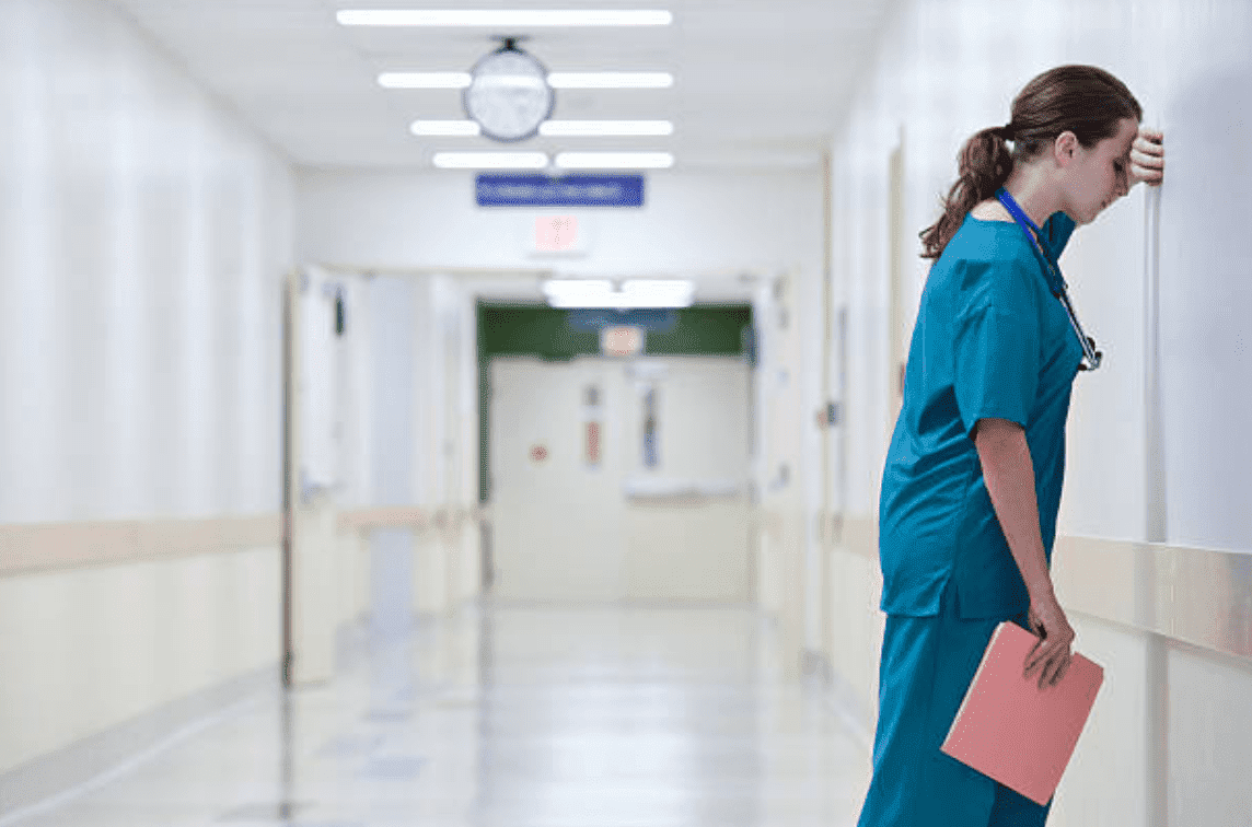 Female nurse looking frustrated, resting her head on a hospital wall | Source: Getty Images