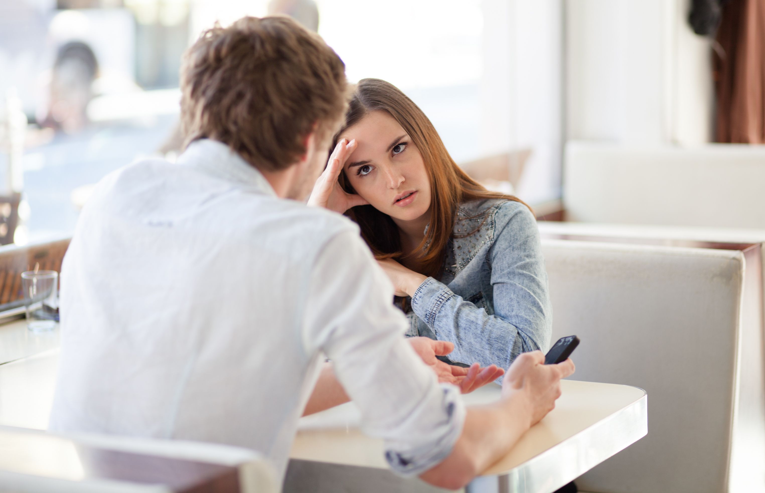 A woman looks upset while sitting in front of a man. | Source: Shutterstock
