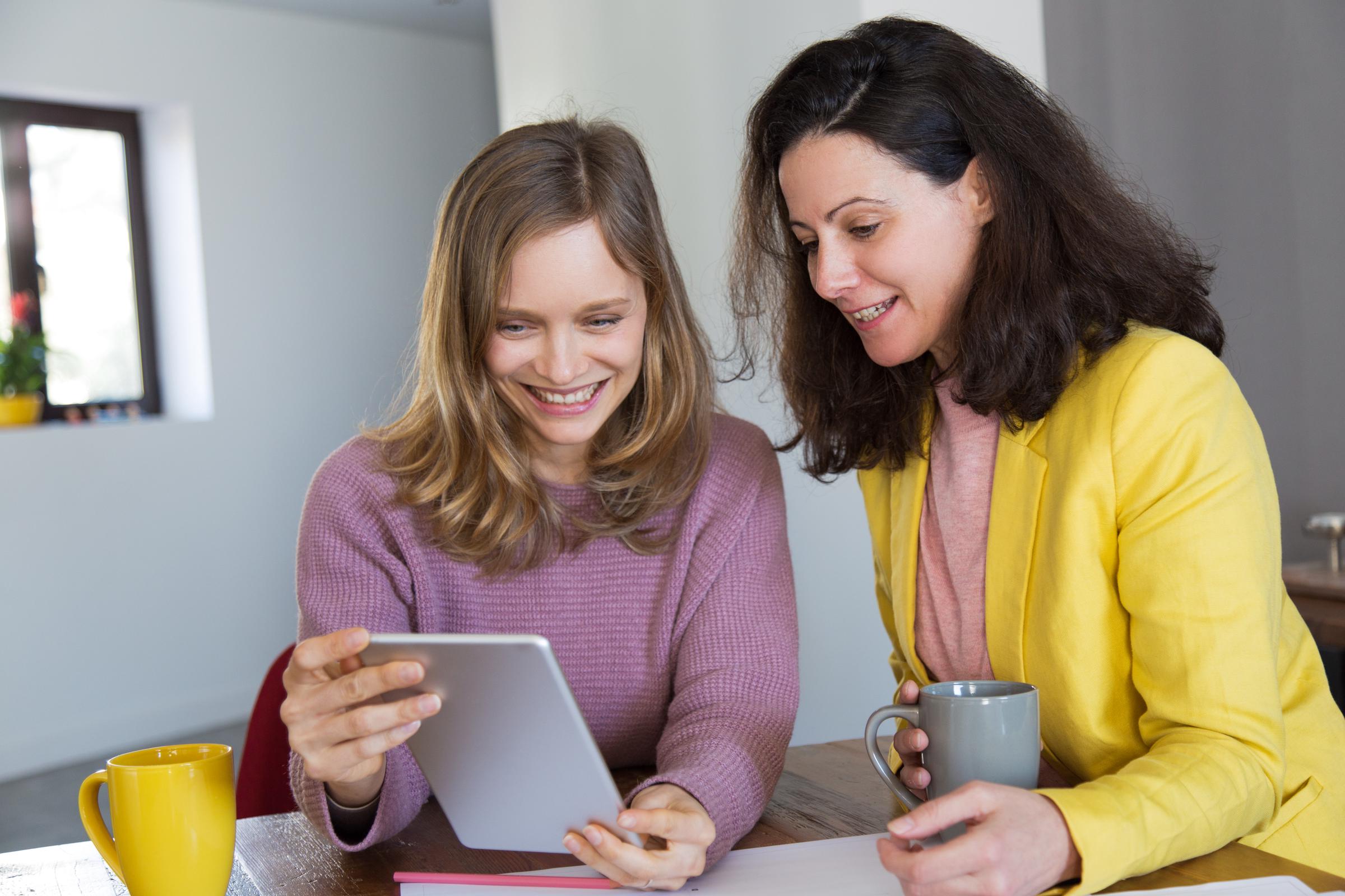 Two friends looking at a tablet | Source: Freepik