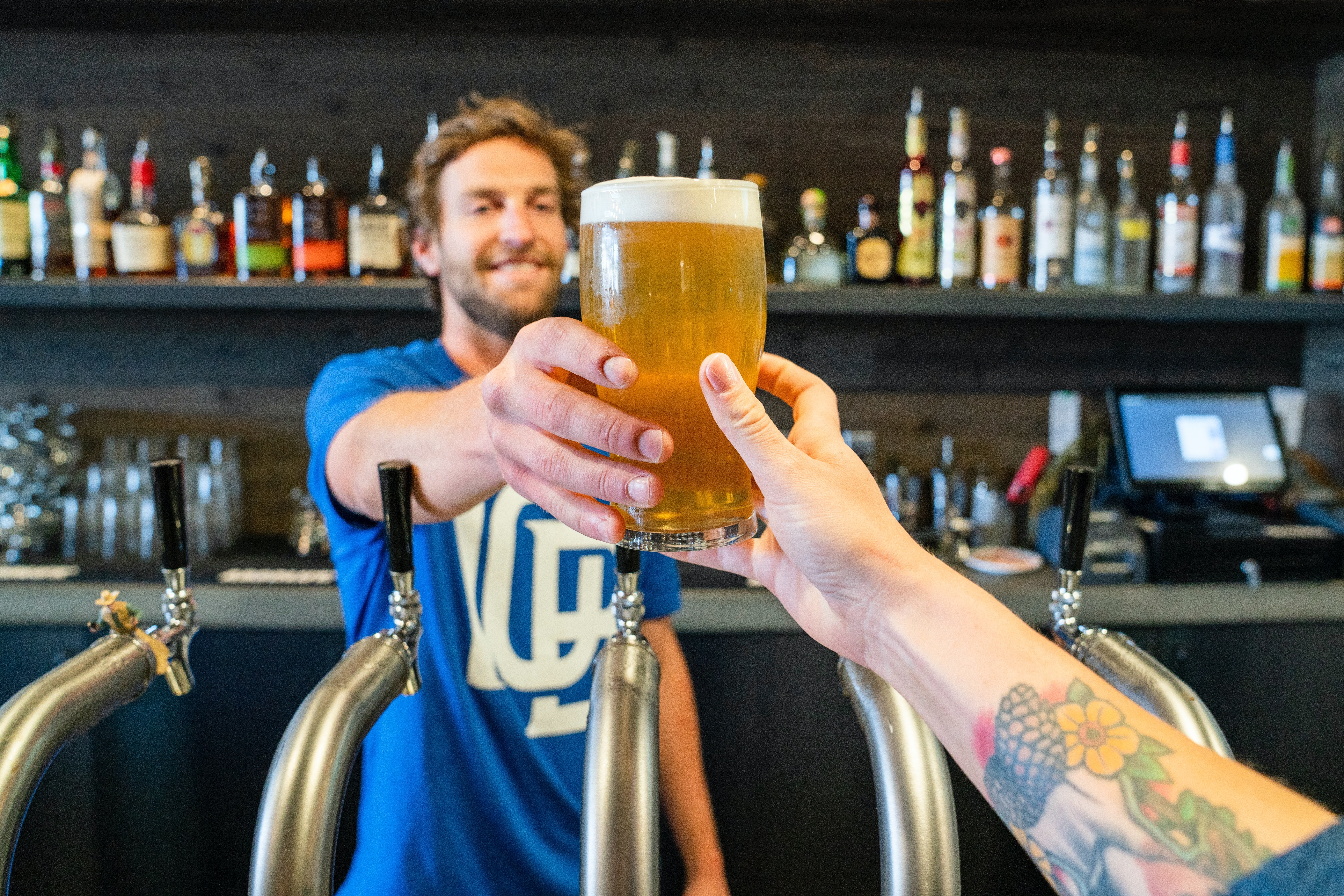 A bartender handing a beer over to a patron. | Photo: Pexels/ ELEVATE