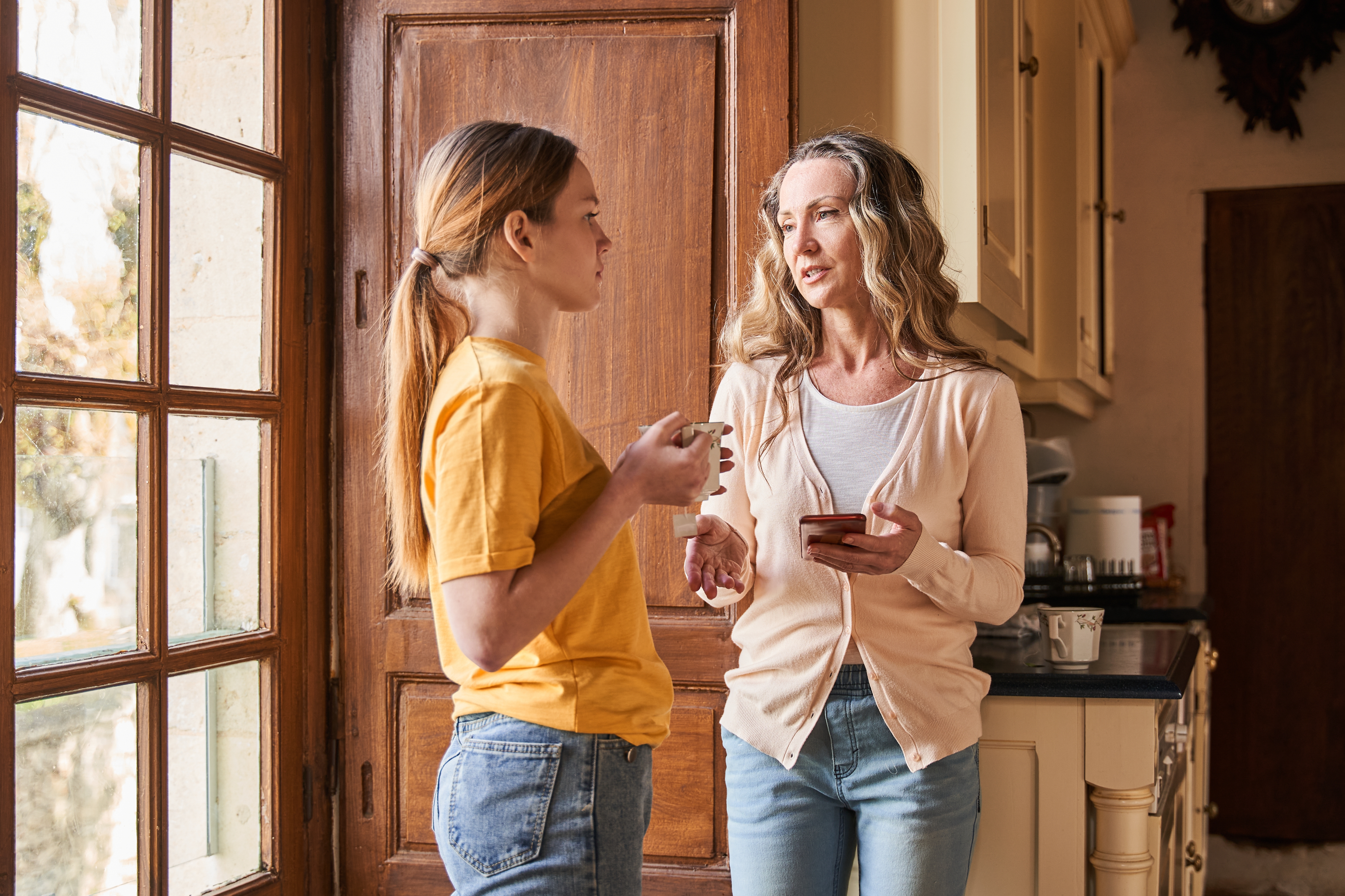 A woman talking to her daughter while standing near the door | Source: Shutterstock