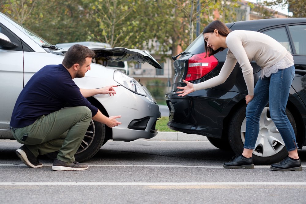 Un hombre y una mujer discuten por el choque de sus vehículos. | Foto: Shutterstock