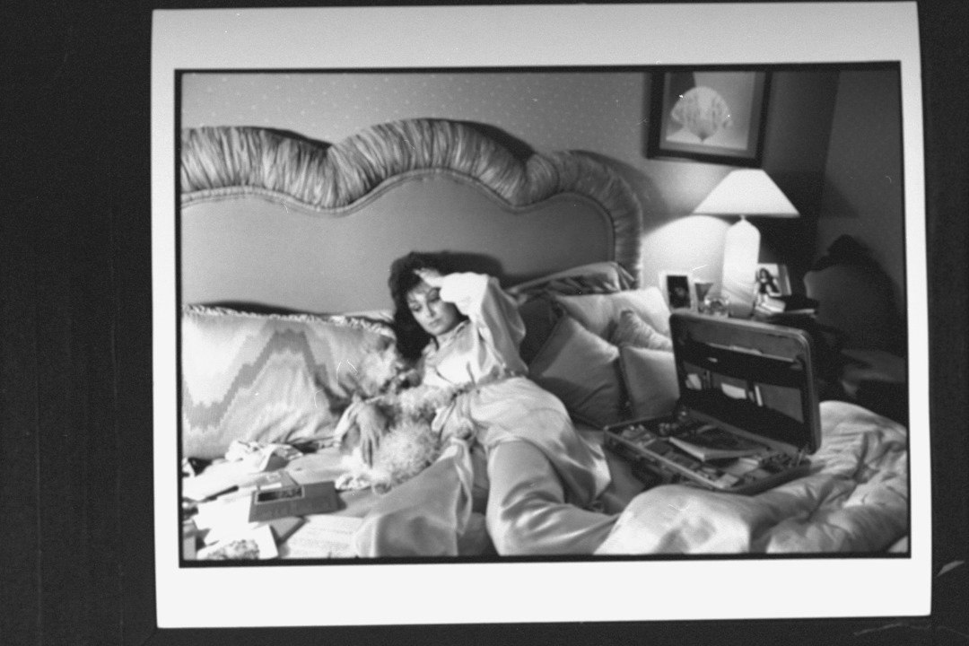 Naomi Judd, mother of mother-daughter C/W duo, lying in bed, going through correspondence while cuddling dog; suffering from chronic hepatitis. | Source: Getty Images