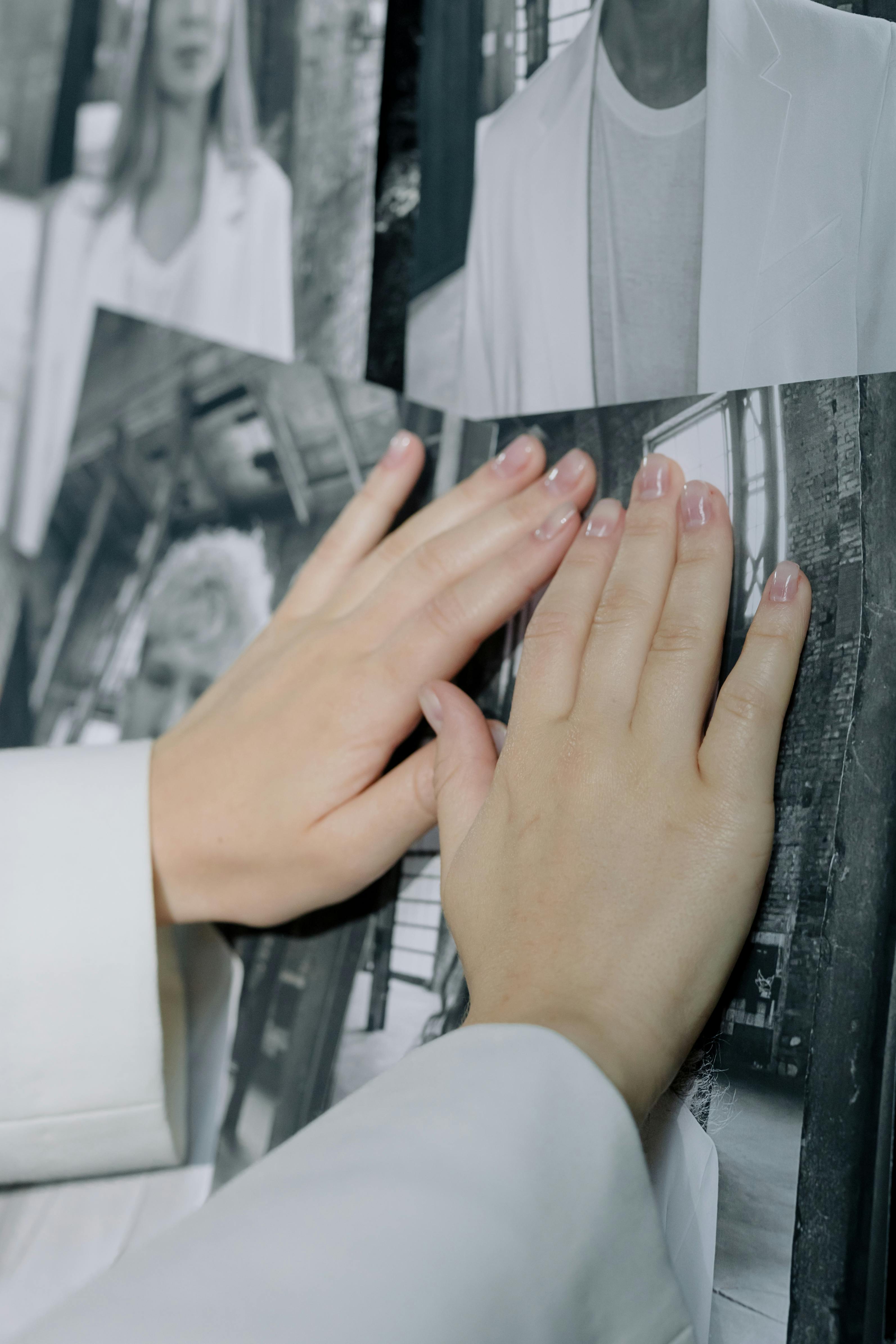Hands attaching photographs to a wall | Source: Pexels