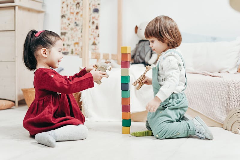 A little boy and girl playing with blocks in their room | Source: Pexels