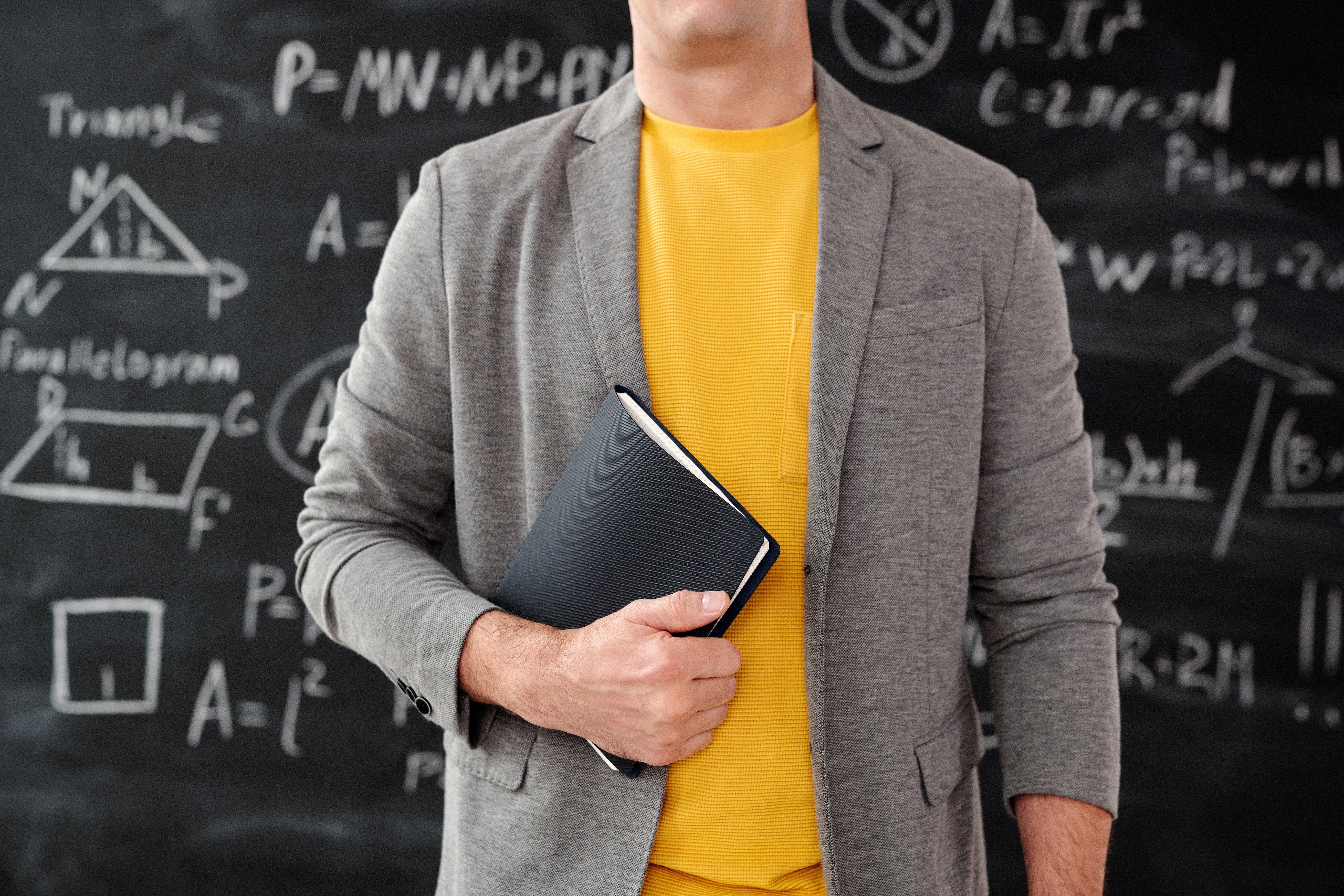 Teacher standing in fornt of a blackboard. | Pexels/ Max Fischer