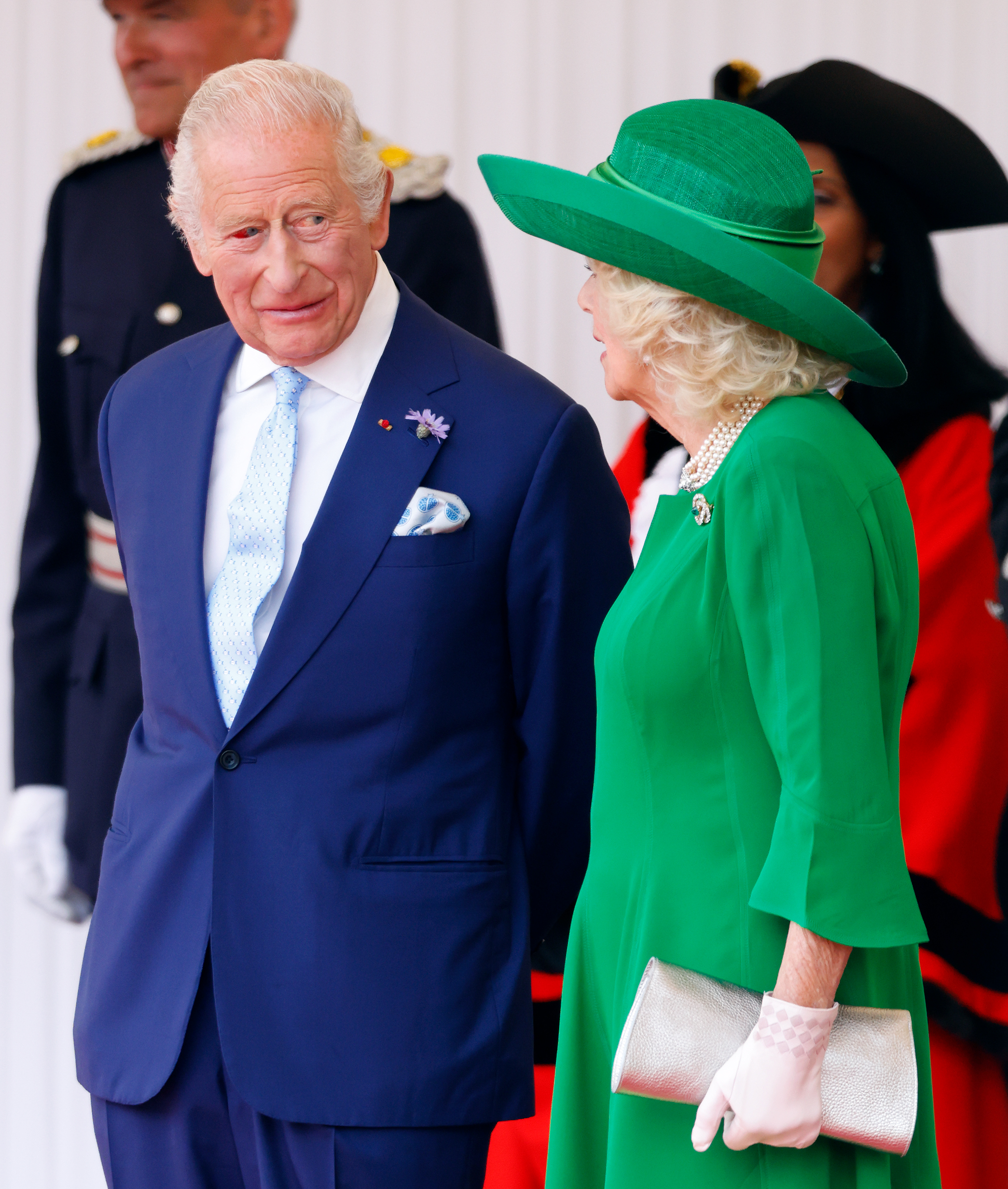 King Charles III, with a noticeably red right eye, stands beside Queen Camilla at the formal event. The queen's emerald ensemble adds brightness to the moment, as the couple leads the first French state visit in nearly two decades.