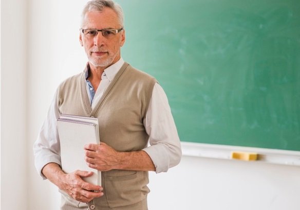 Profesor de pie y sosteniendo una carpeta de apuntes. | Foto: Freepik