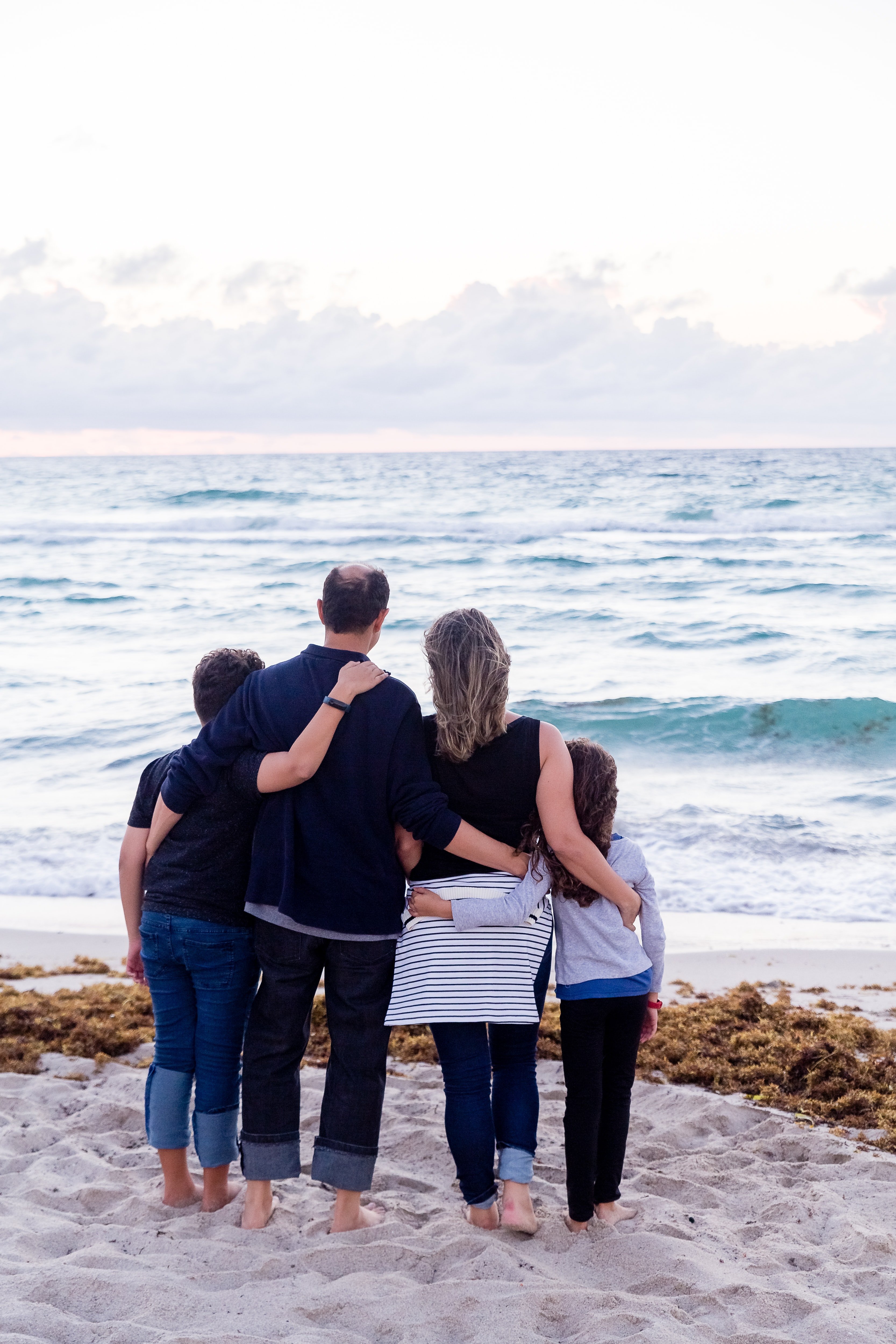 Una familia de cuatro comparte un abrazo frente al mar. | Foto: Unsplash