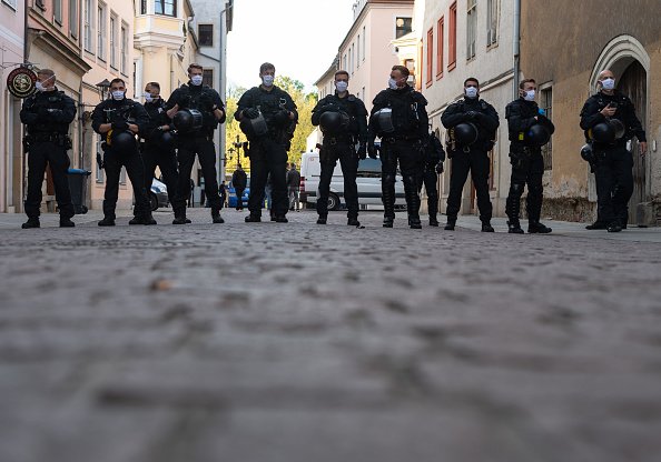 Des policiers se tiennent en marge d'une manifestation d'opposants aux mesures de la Corona. | Photo : Getty Images