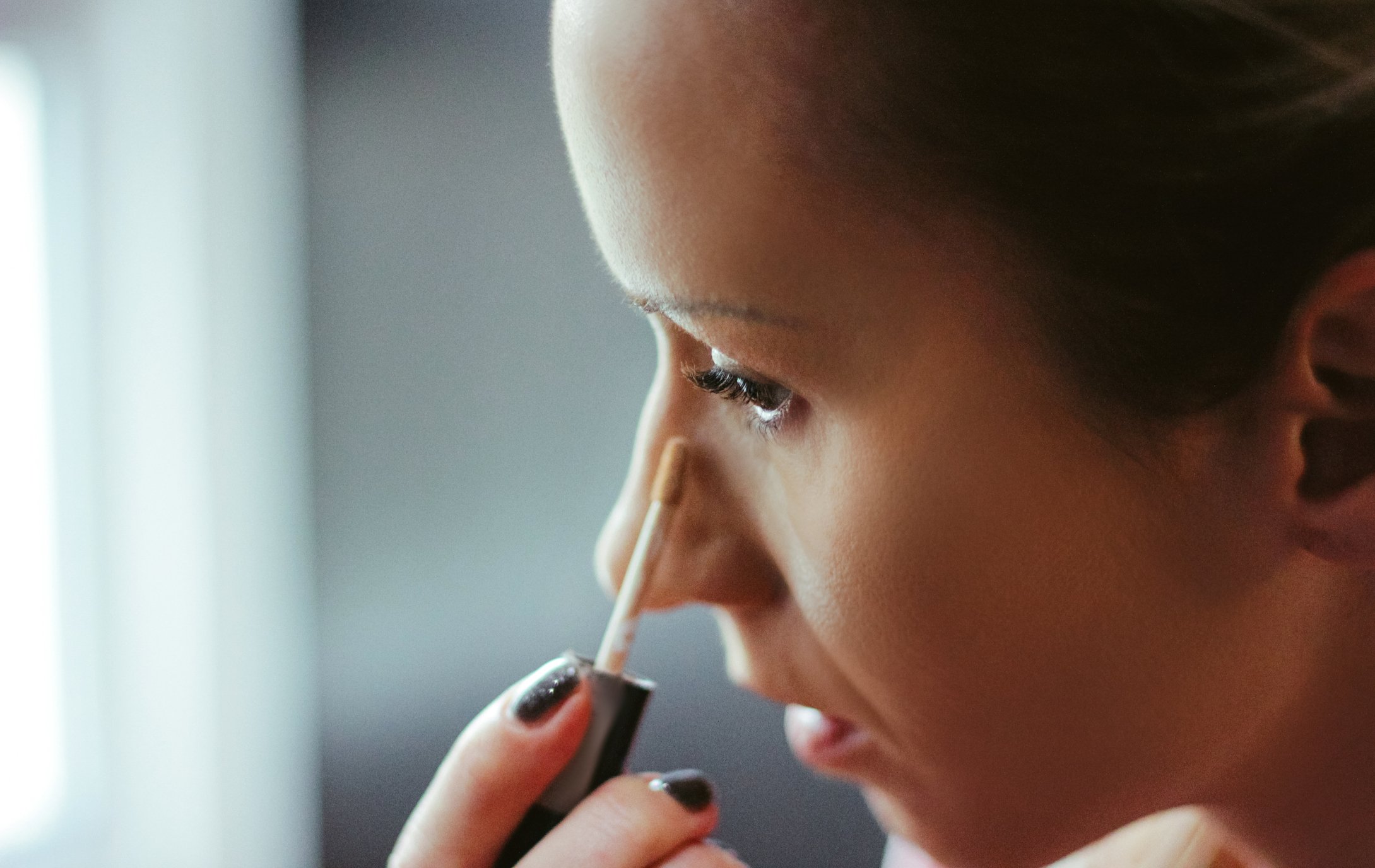 Junge Frauen wendet Concealer unter den Augen an I Quelle: Getty Images