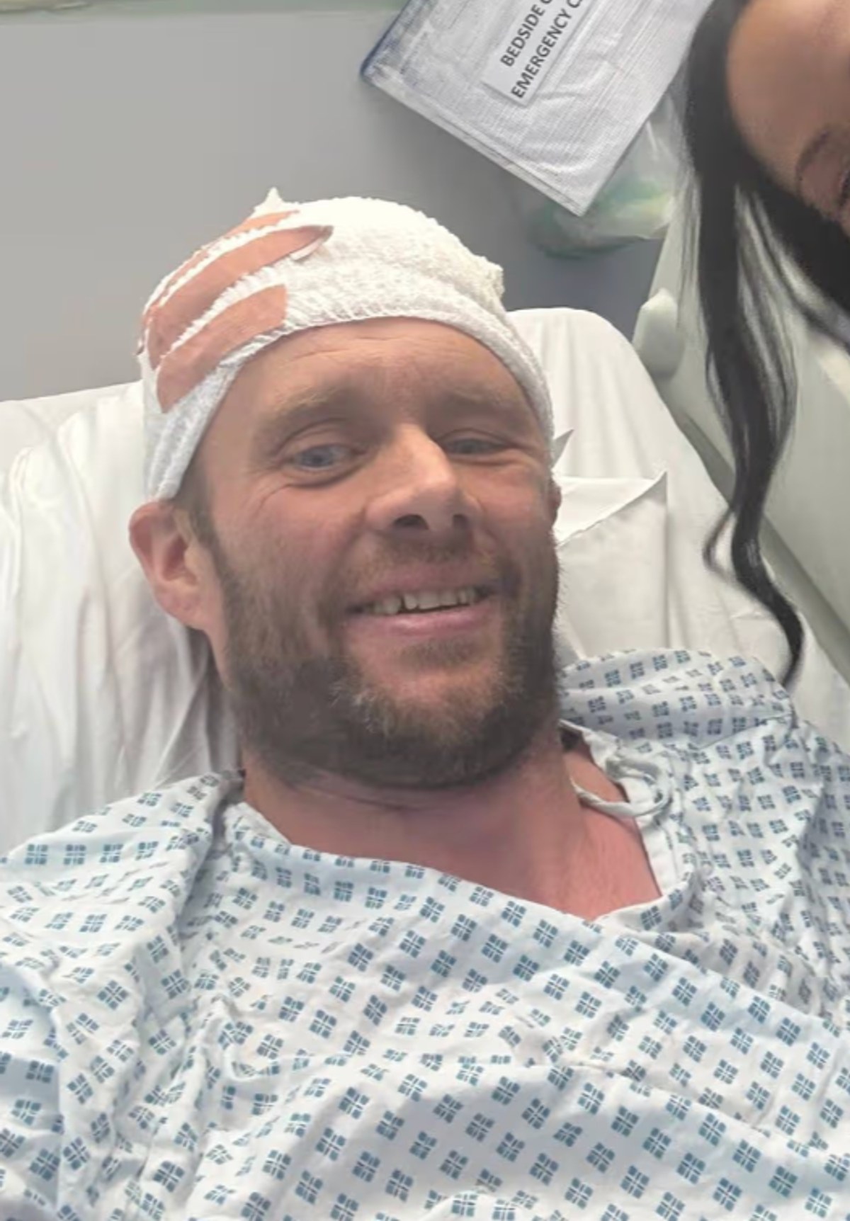 A Warrior's Smile: From his hospital bed, Smith offers a brave, defiant smile despite the visible bandaging from brain surgery. With just four months to live, the gold medallist faces his toughest battle yet — and the world watches in awe at his unbreakable spirit. | Source: Facebook/Daily Record