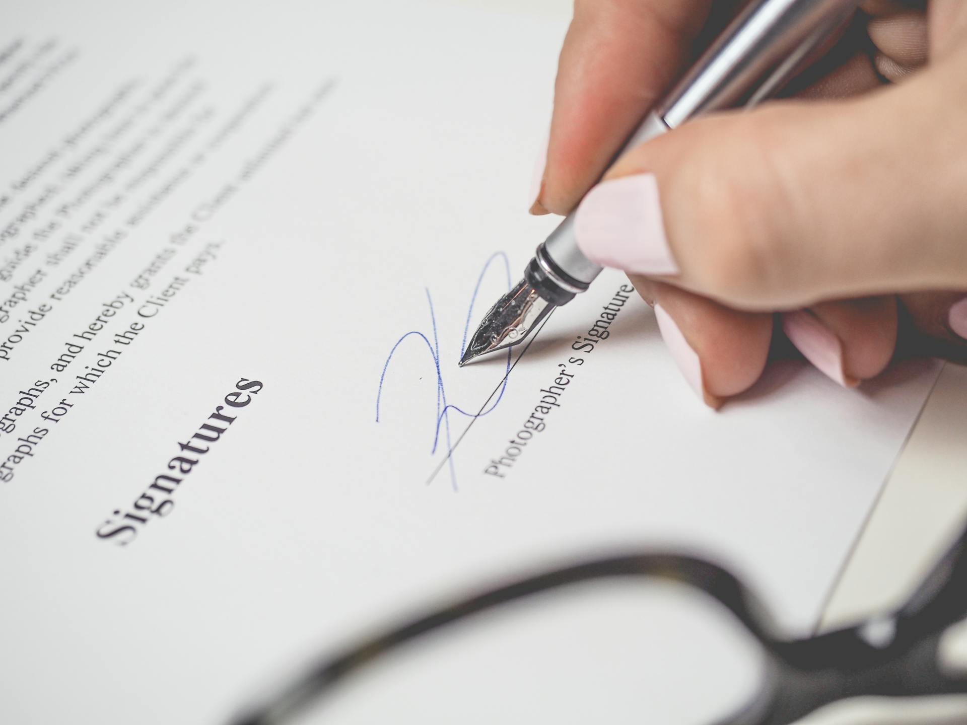 A close-up shot of a woman signing a document | Source: Pexels