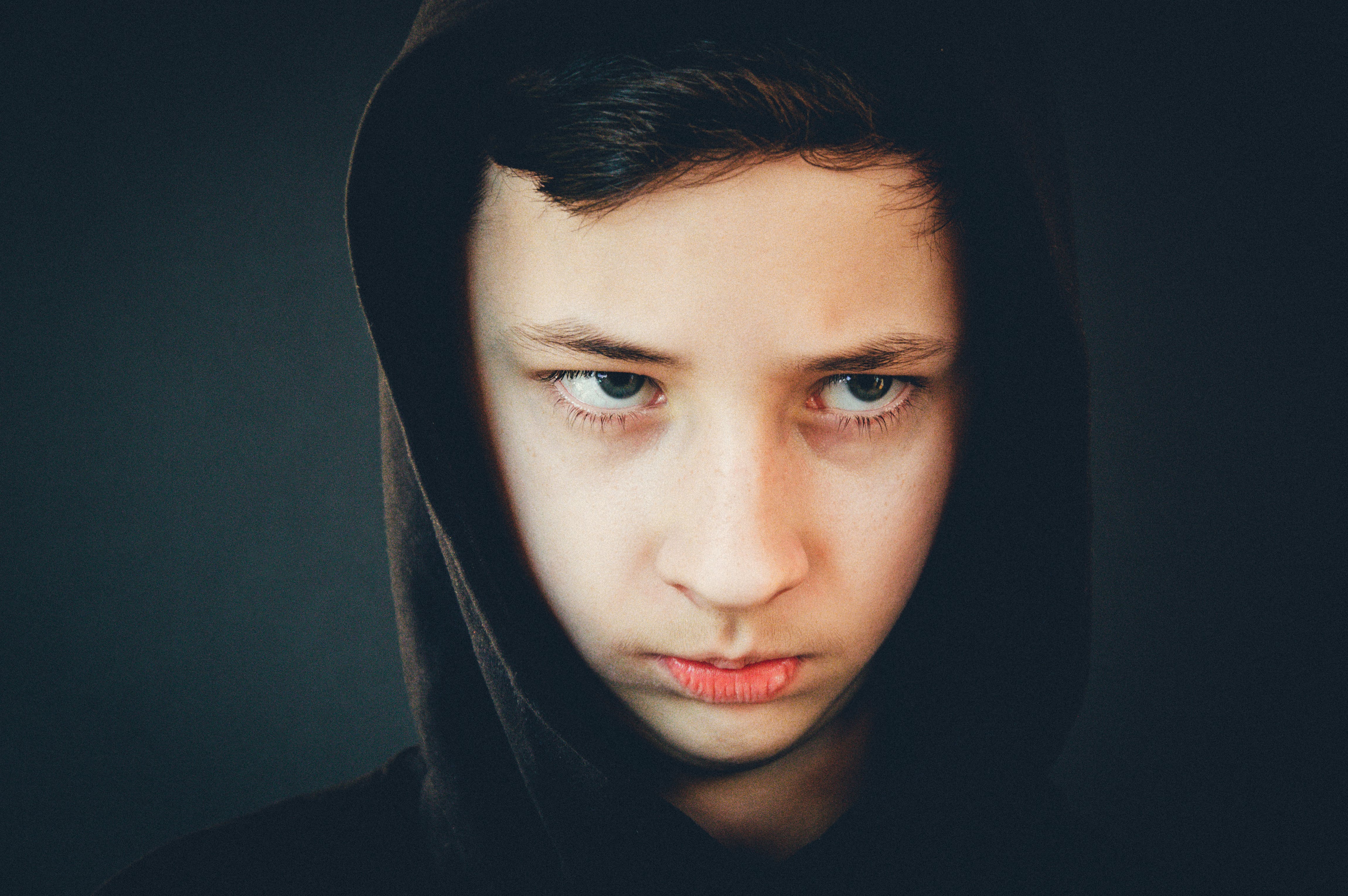 An upset boy looking glum while wearing a hoodie | Source: Pexels
