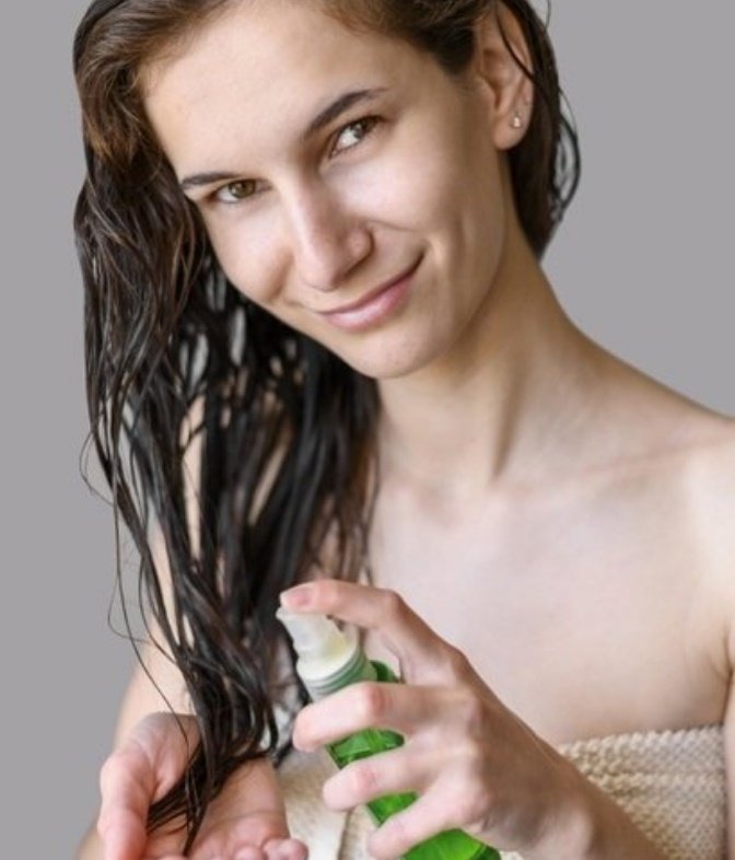 Mujer aplicando un producto en su cabello. | Foto: Freepik