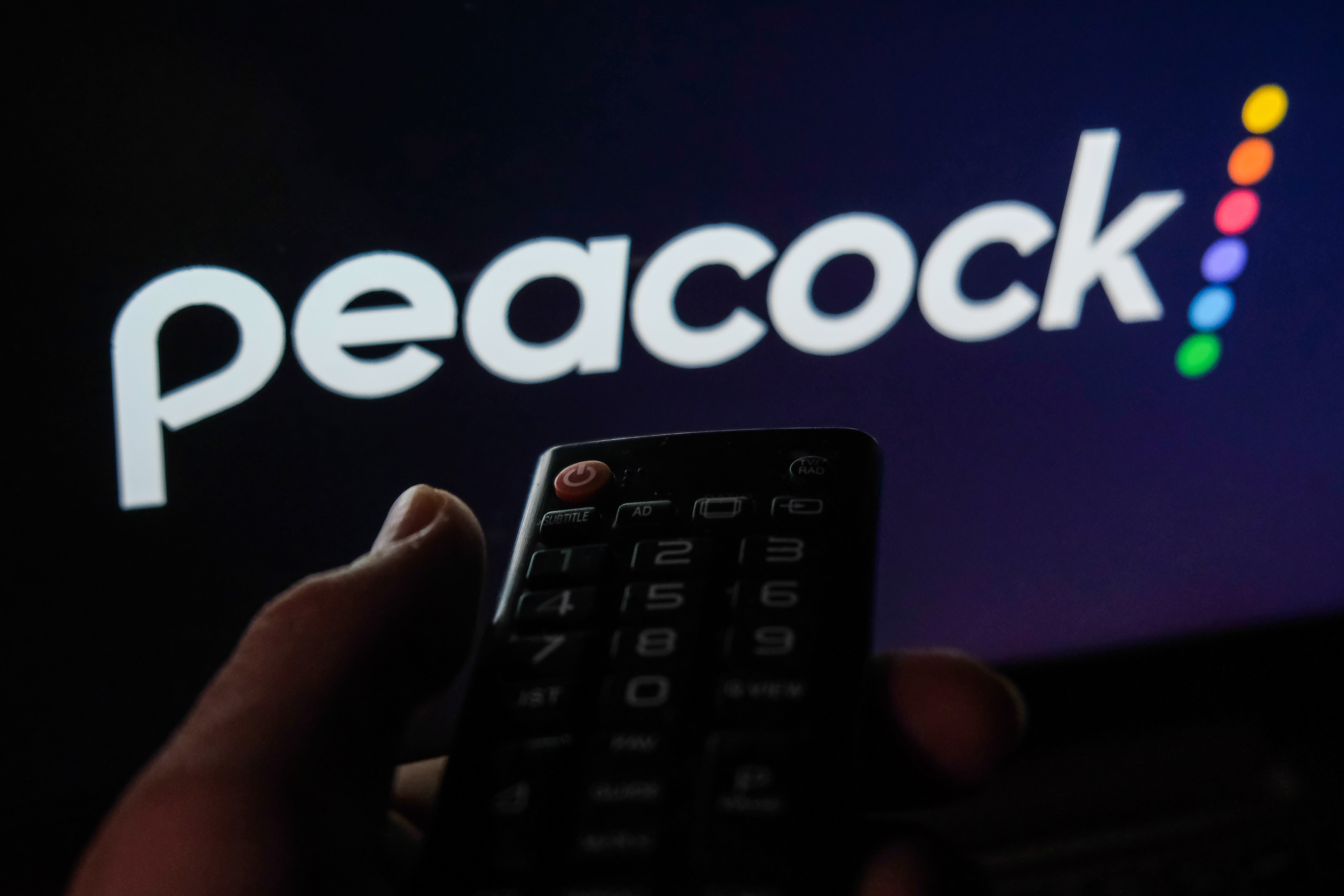 A photo of a hand holding a TV remote in front of the Peacock logo taken in Krakow, Poland on February 6, 2022 | Source: Getty Images