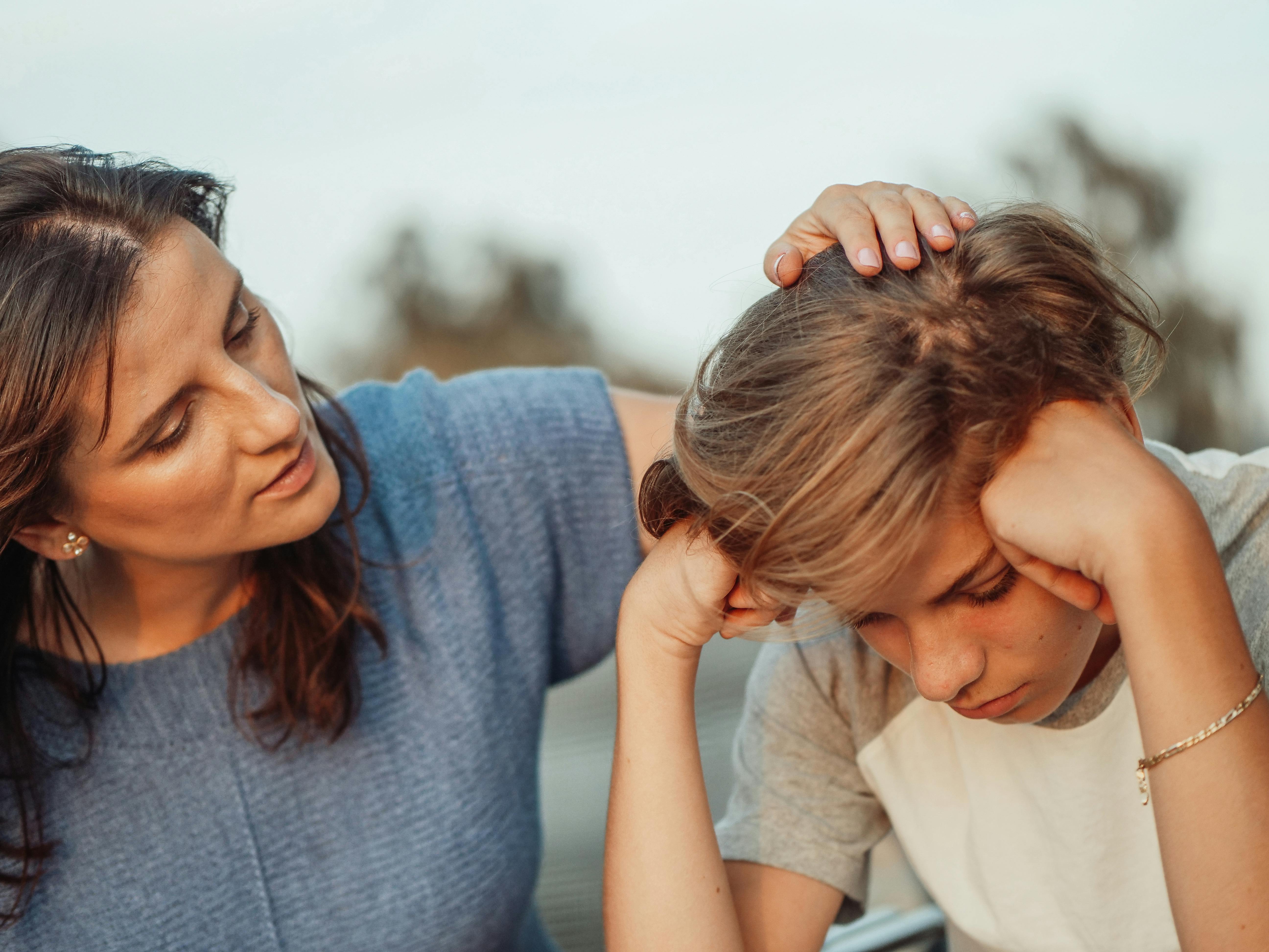 A woman comforting his son by placing her hand on his head | Source: Pexels