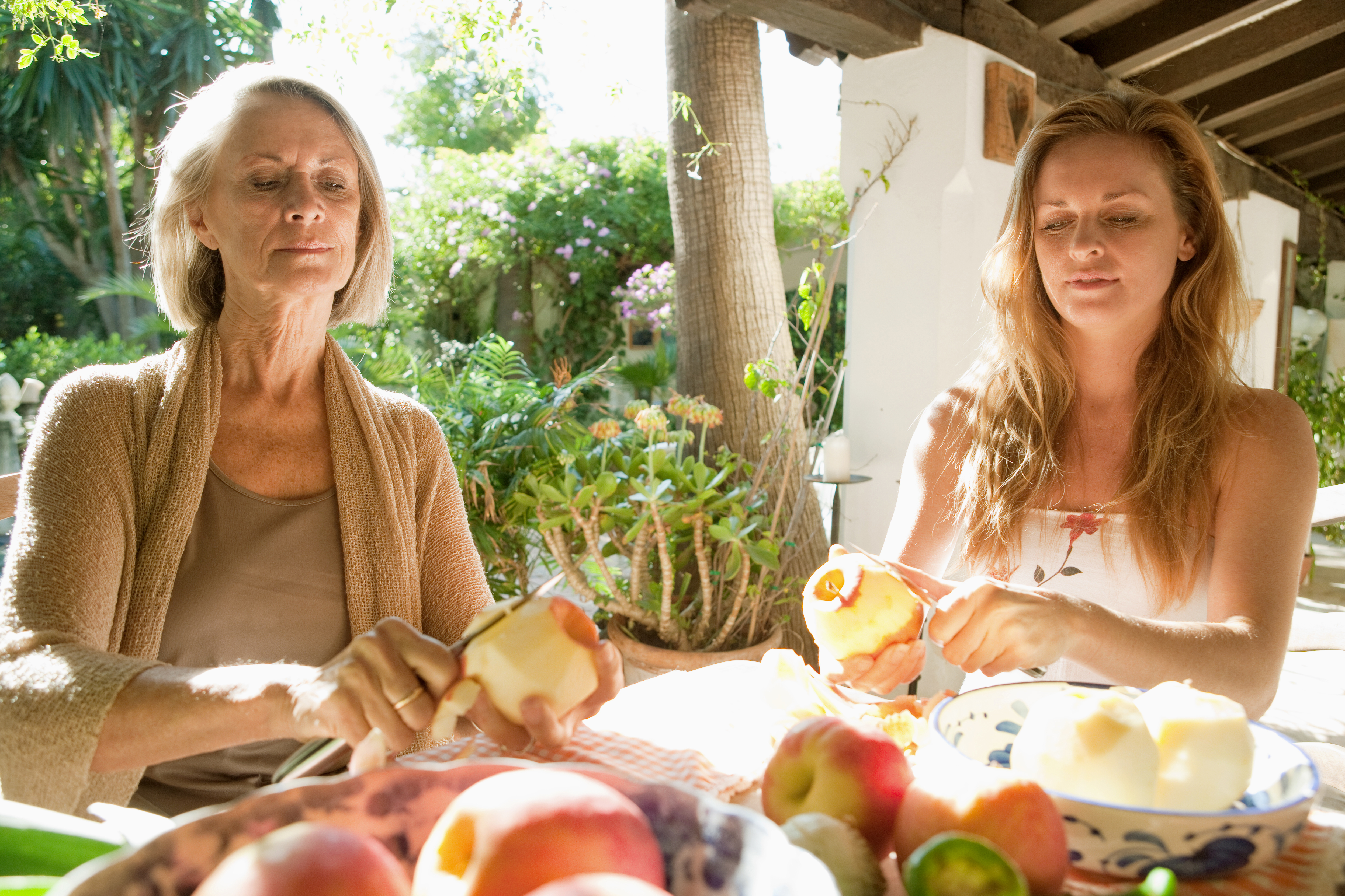 Two women at a dining table peeling apples | Source: Shutterstock