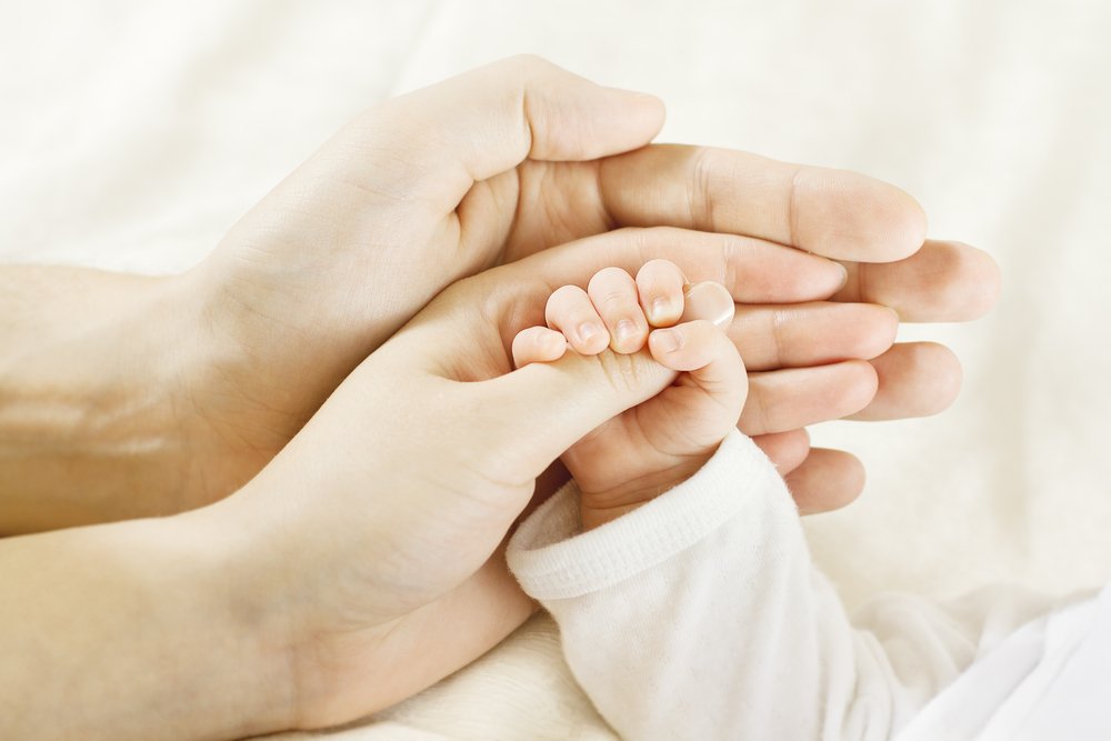 Padres tomando la mano de su bebé. | Foto: Shutterstock.
