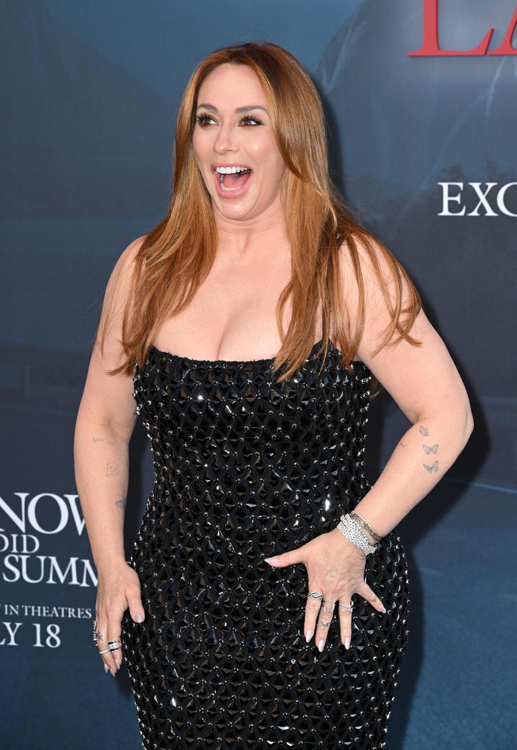Jennifer Love Hewitt beams on the carpet with an animated smile, exuding confidence as she engages with the cameras.