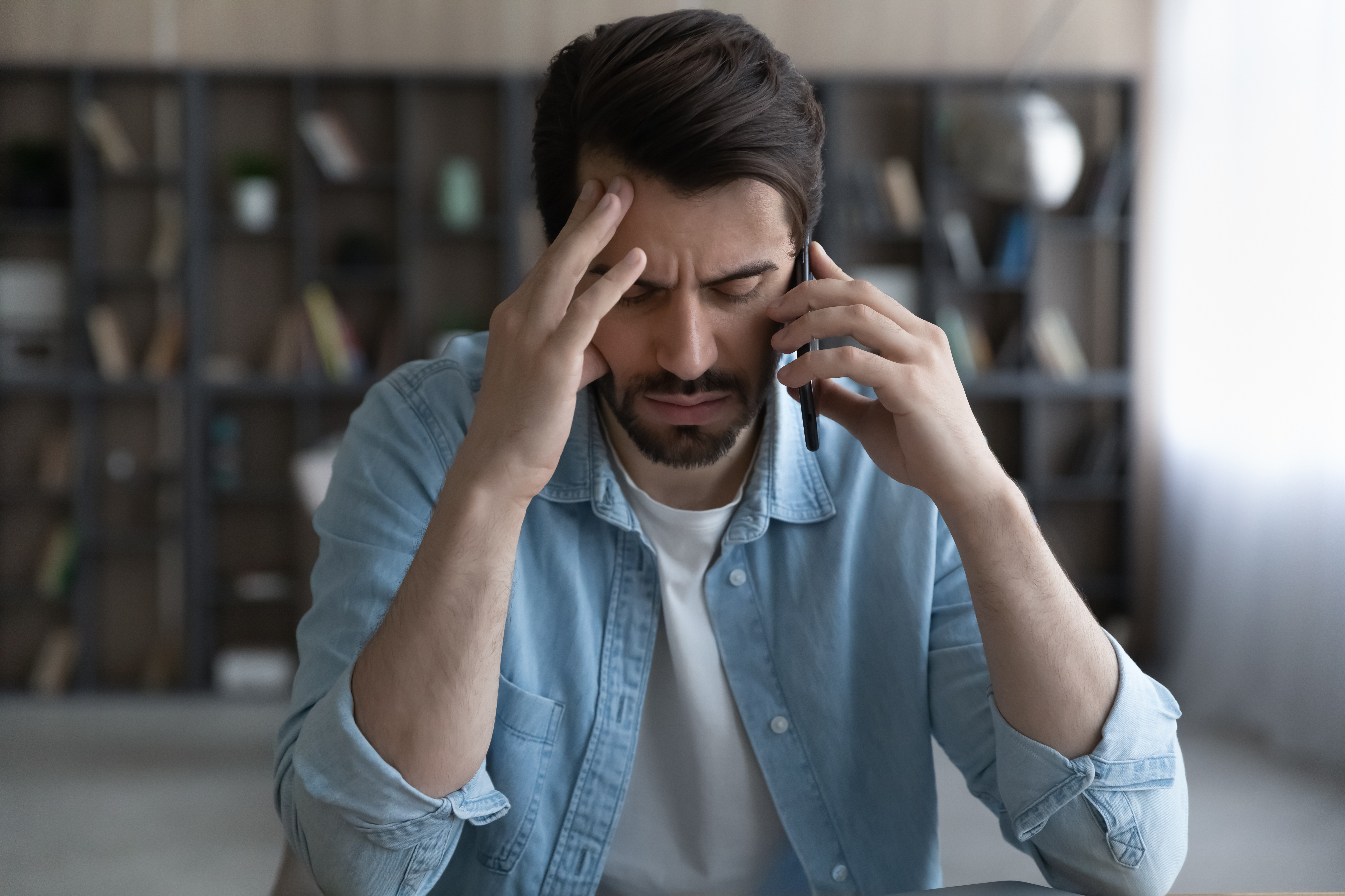 Stressed young man talking on the phone | Source: Shutterstock