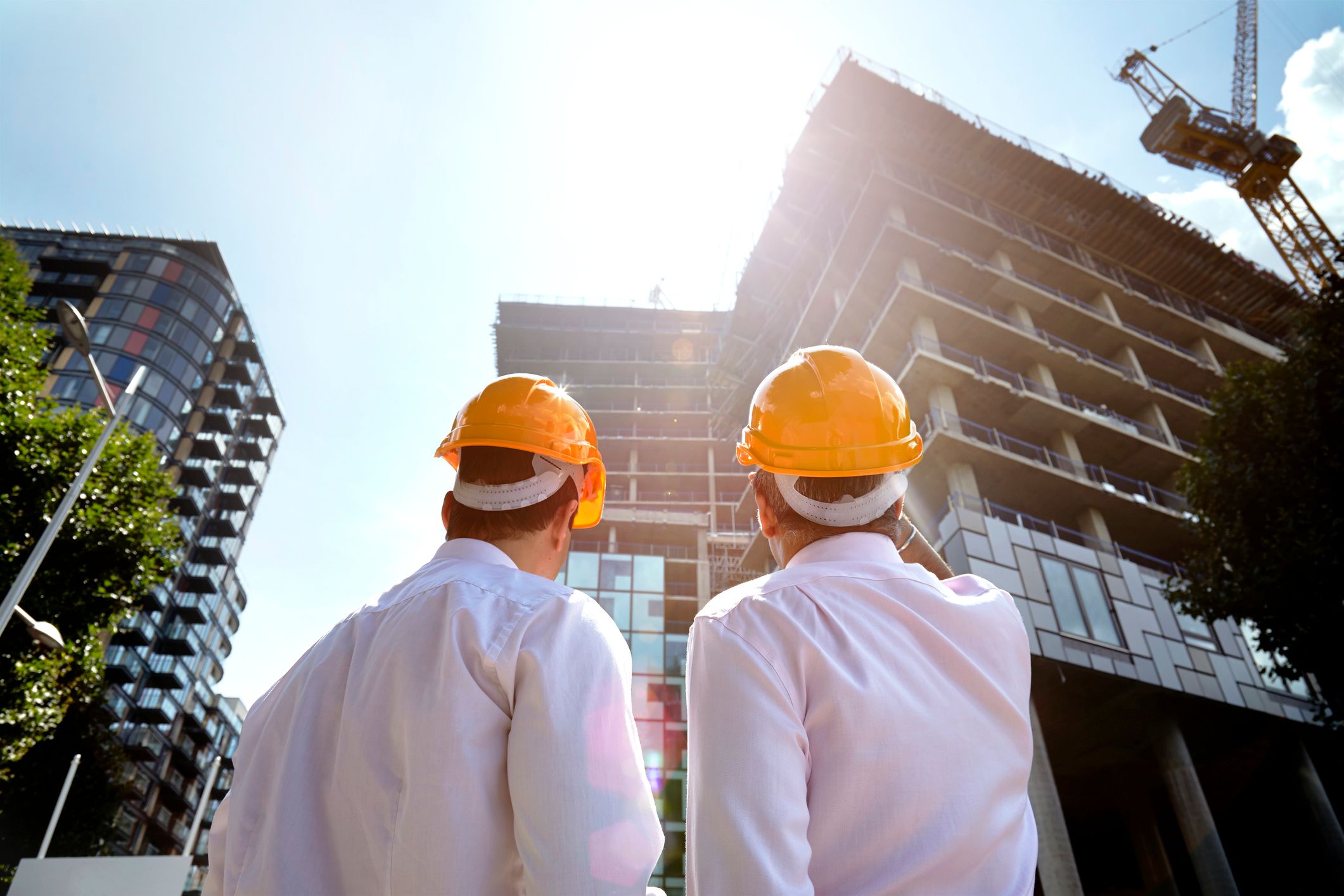 Two construction workers pointing at a building. | Source: Shutterstock