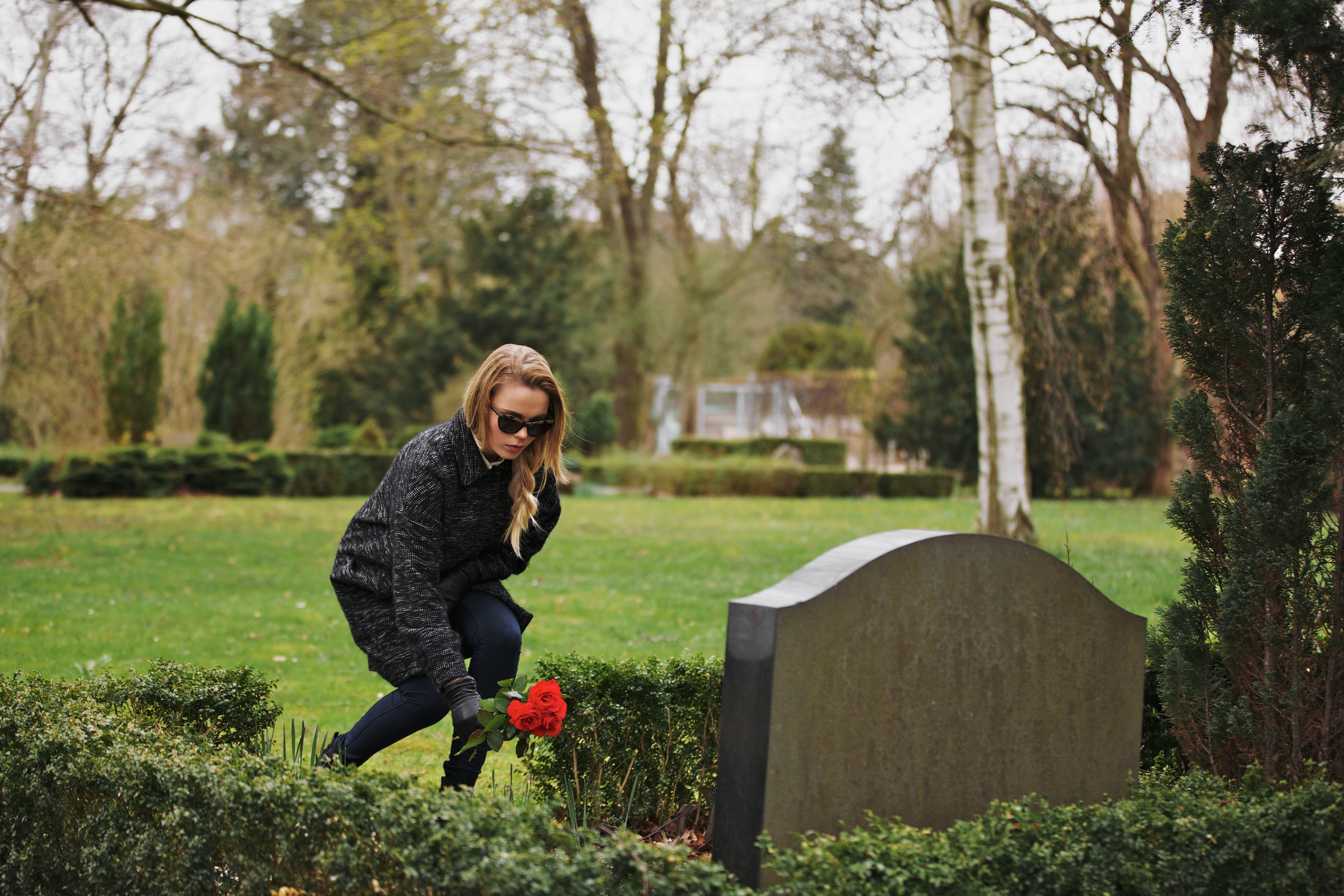 Young woman placing flowers on grave | Source: Shutterstock