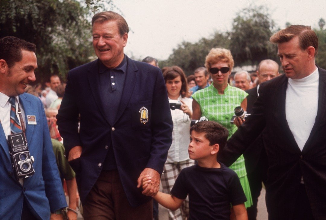 American actor John Wayne holding his son's hand, John Ethan, while on a visit to the Knott's Berry Farm amusement park, Buena Park, California. | Source: Getty Images