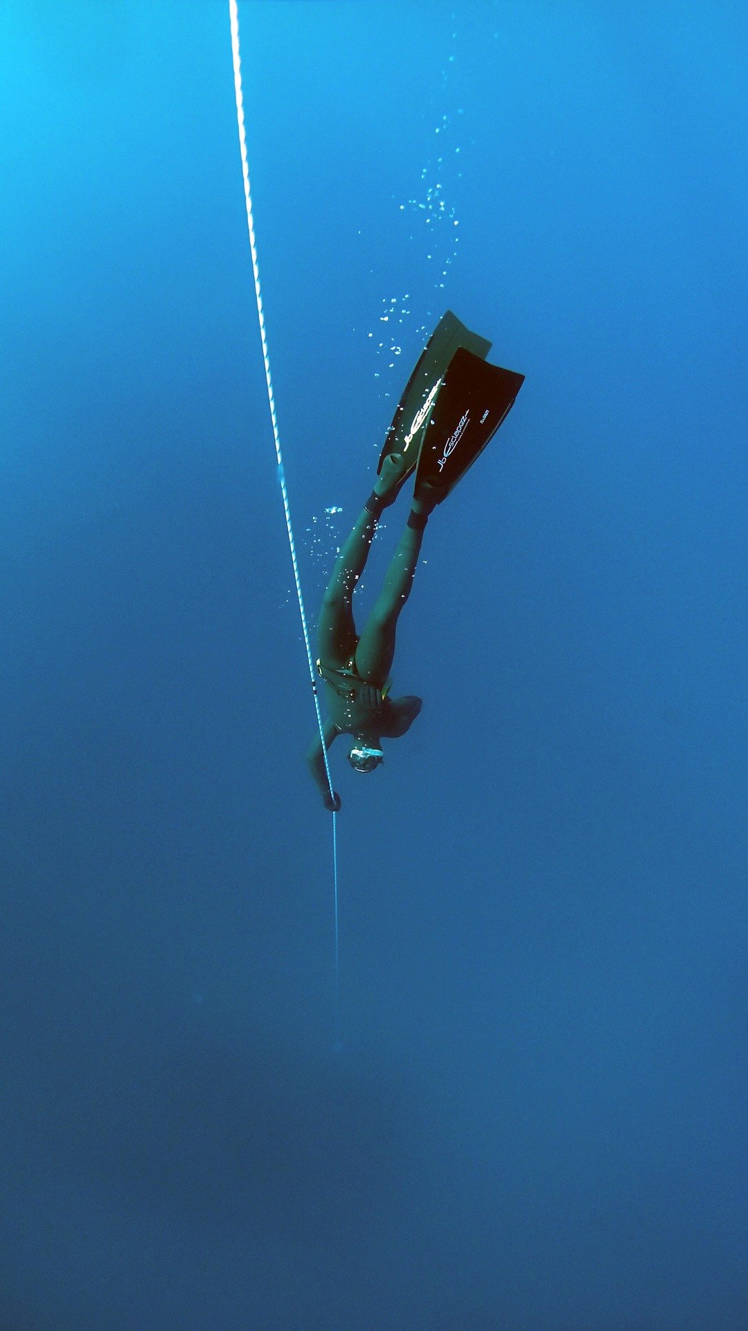 A person dressed in a black wetsuit while free diving in the ocean | Photo: Pixabay/Jakob Boman