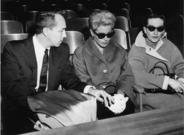 American actor Lana Turner (C), wearing dark sunglasses, sits next to her ex-husband, Stephen Crane, in a courtroom during the murder trial of their daughter, Cheryl Crane. Crane, who had stabbed Turner's gangster ex-boyfriend Johnny Stompanato, was acquitted for justifiable homicide.1958. | Source: Getty Images